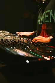 Dj mixing music on a soundboard with hands.