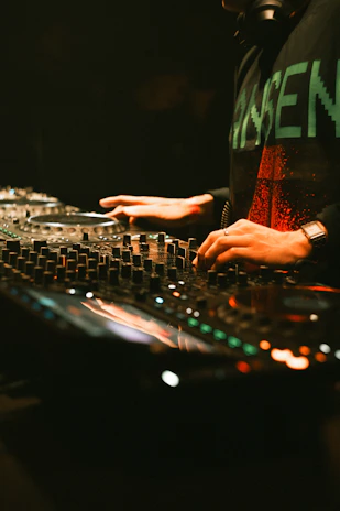 Dj mixing music on a soundboard with hands.