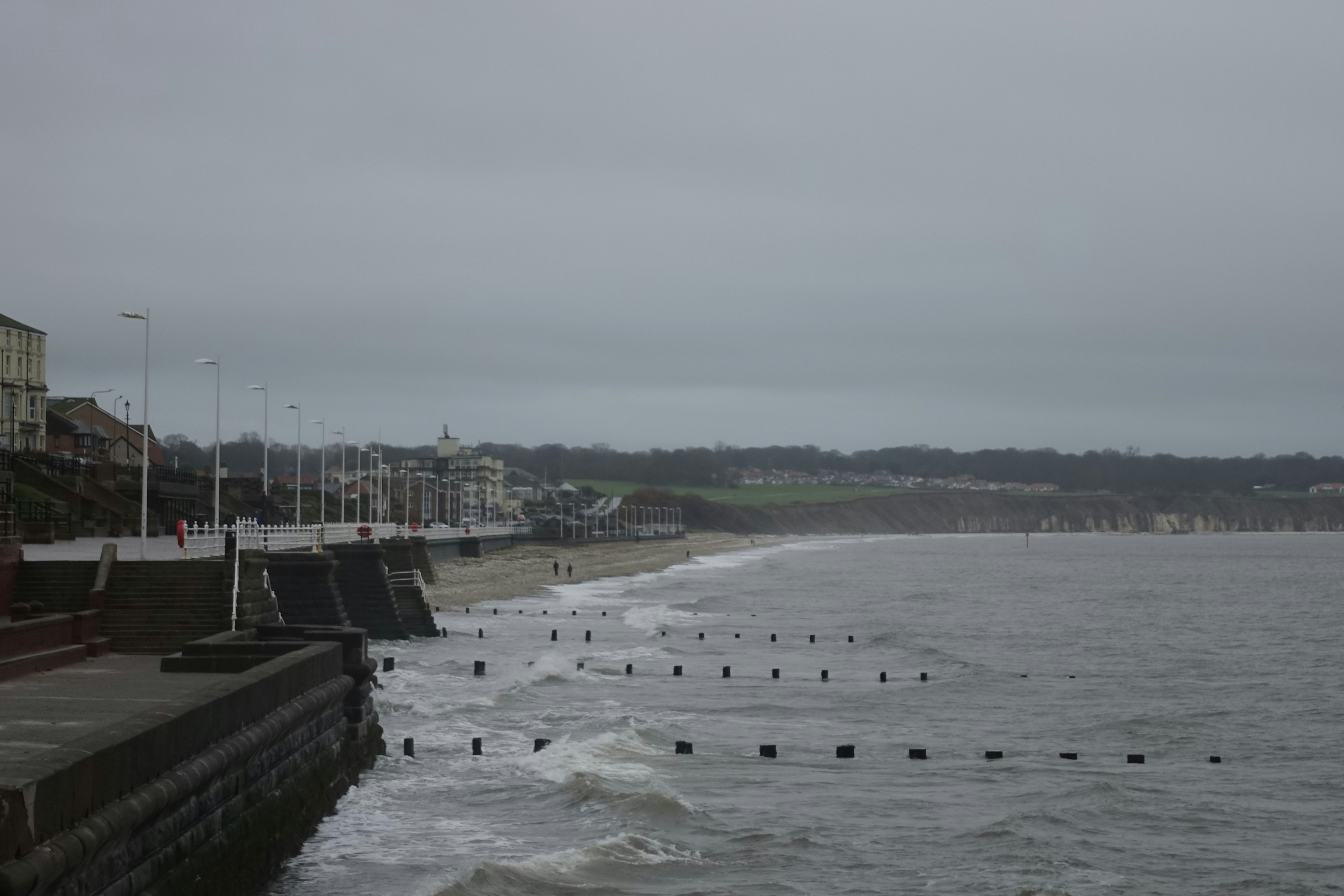 Ocean waves crash onto a beach with buildings in background