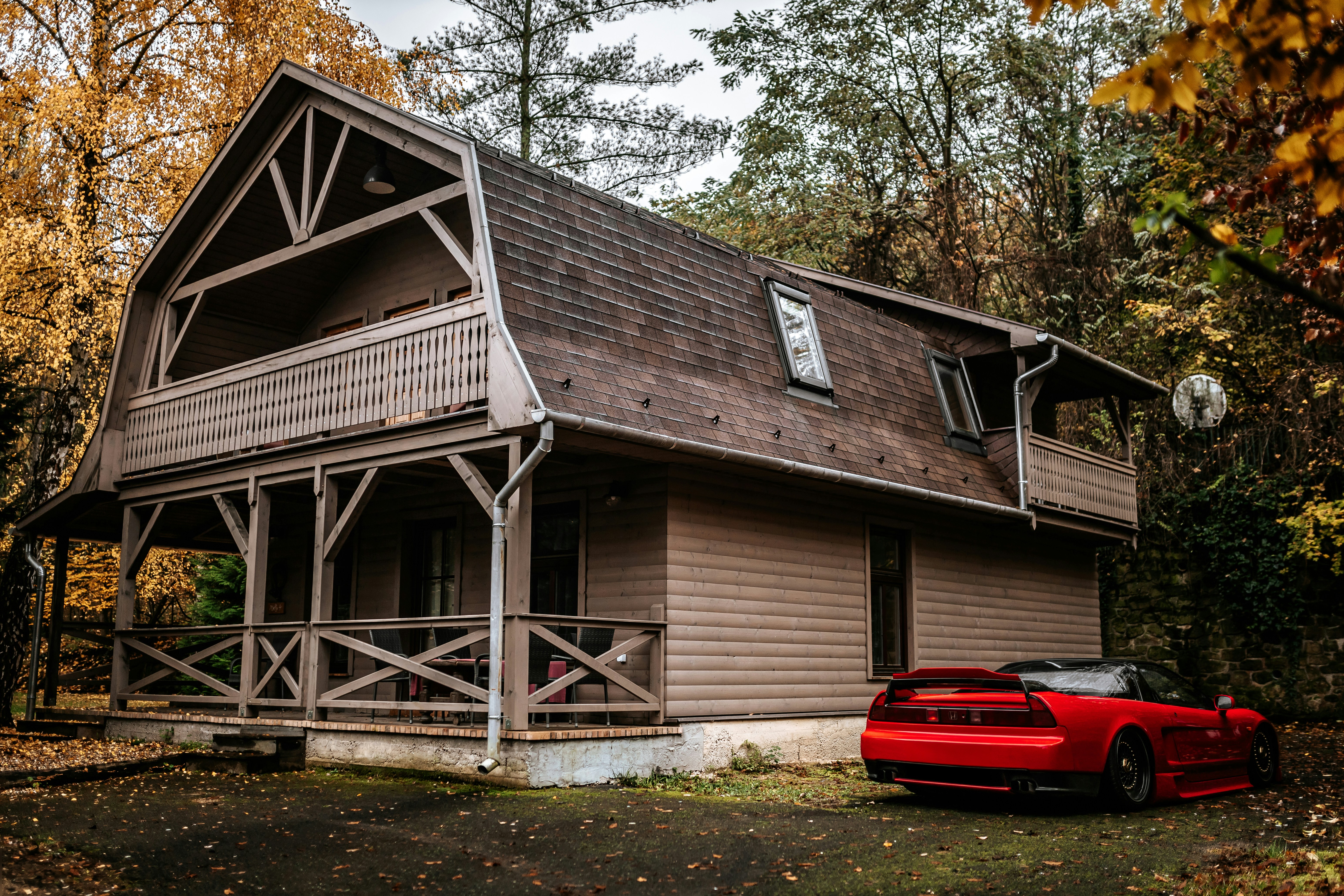 A rustic barn-style house with a red sports car.