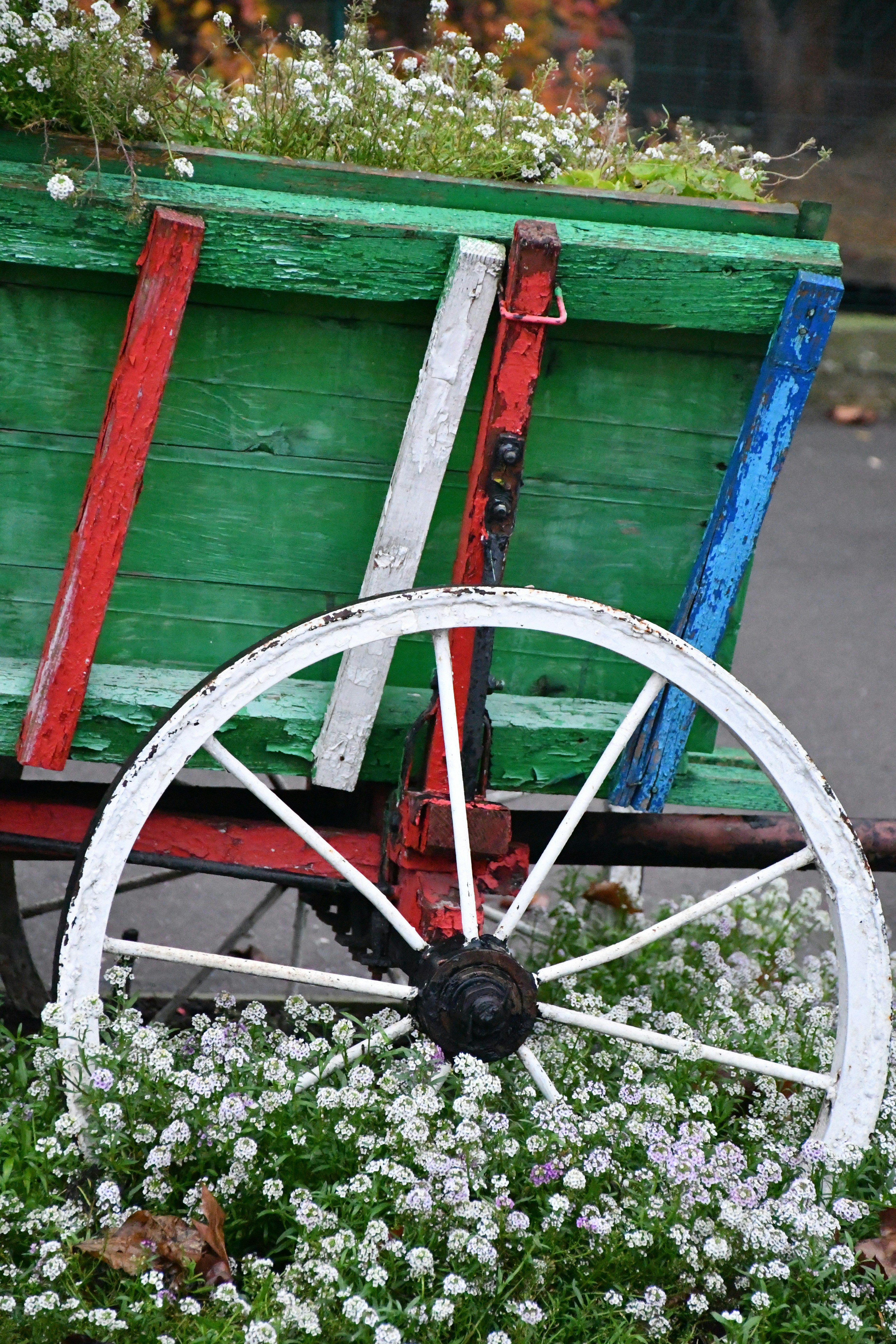 花と白い車輪がついたカラフルな木製の荷車