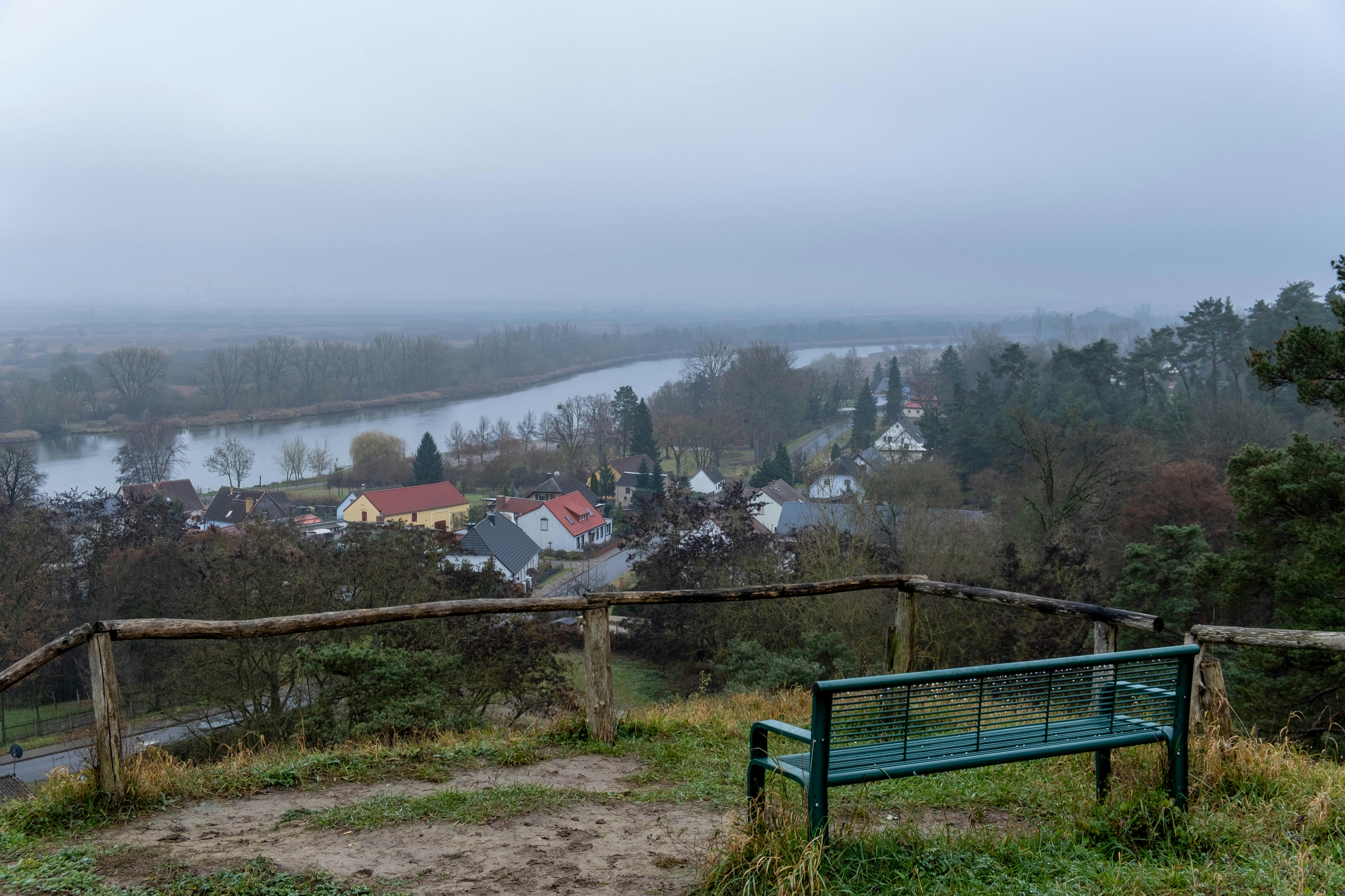 Bench overlooking a foggy village by the river