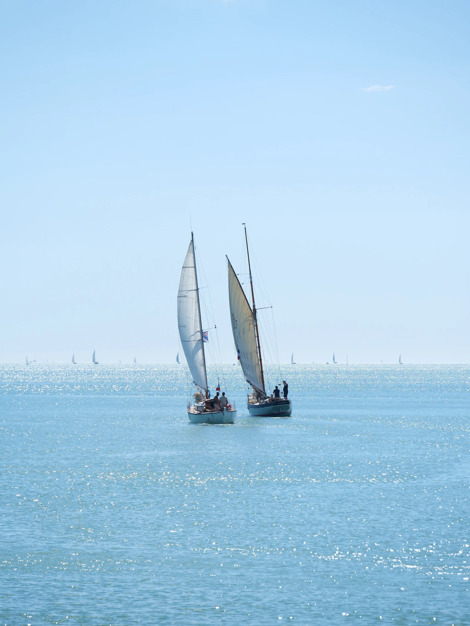 Two classic sailboats racing on sparkling water