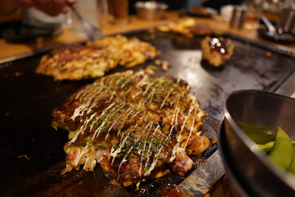 Hiroshima-style okonomiyaki cooking on a teppan grill