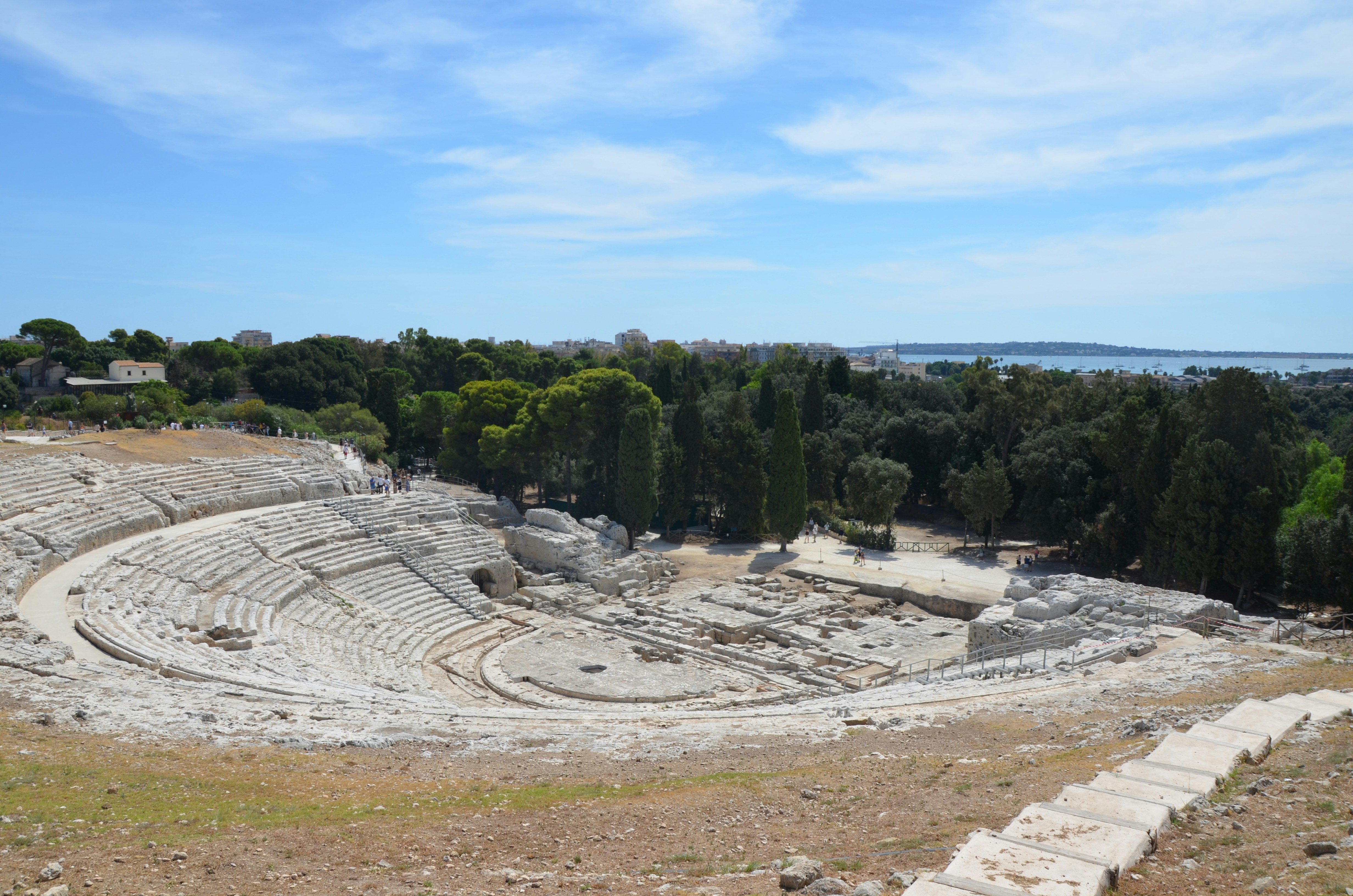 Ruinas de teatros griegos antiguos con árboles y cielo azul