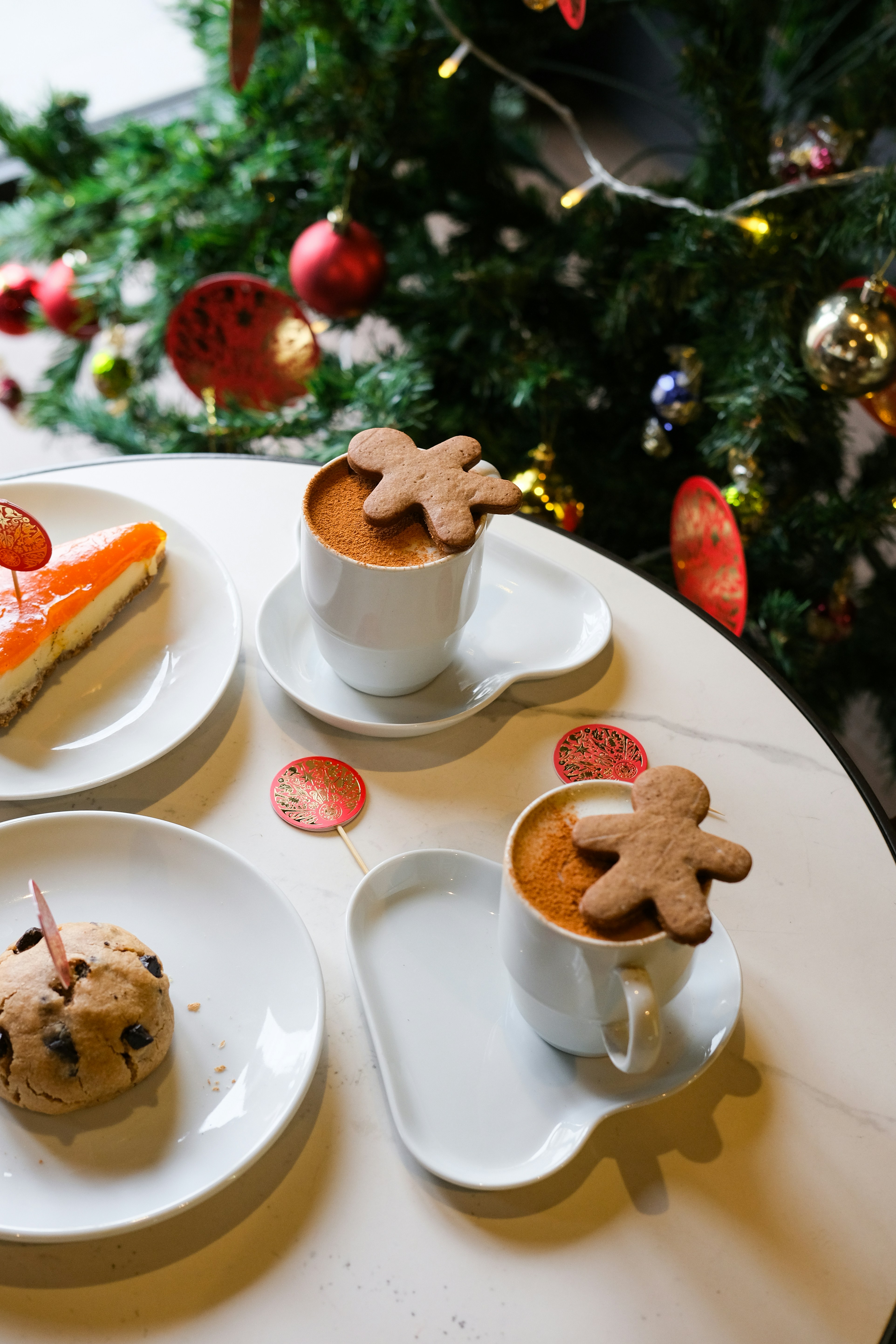 Two coffees with gingerbread men near christmas tree