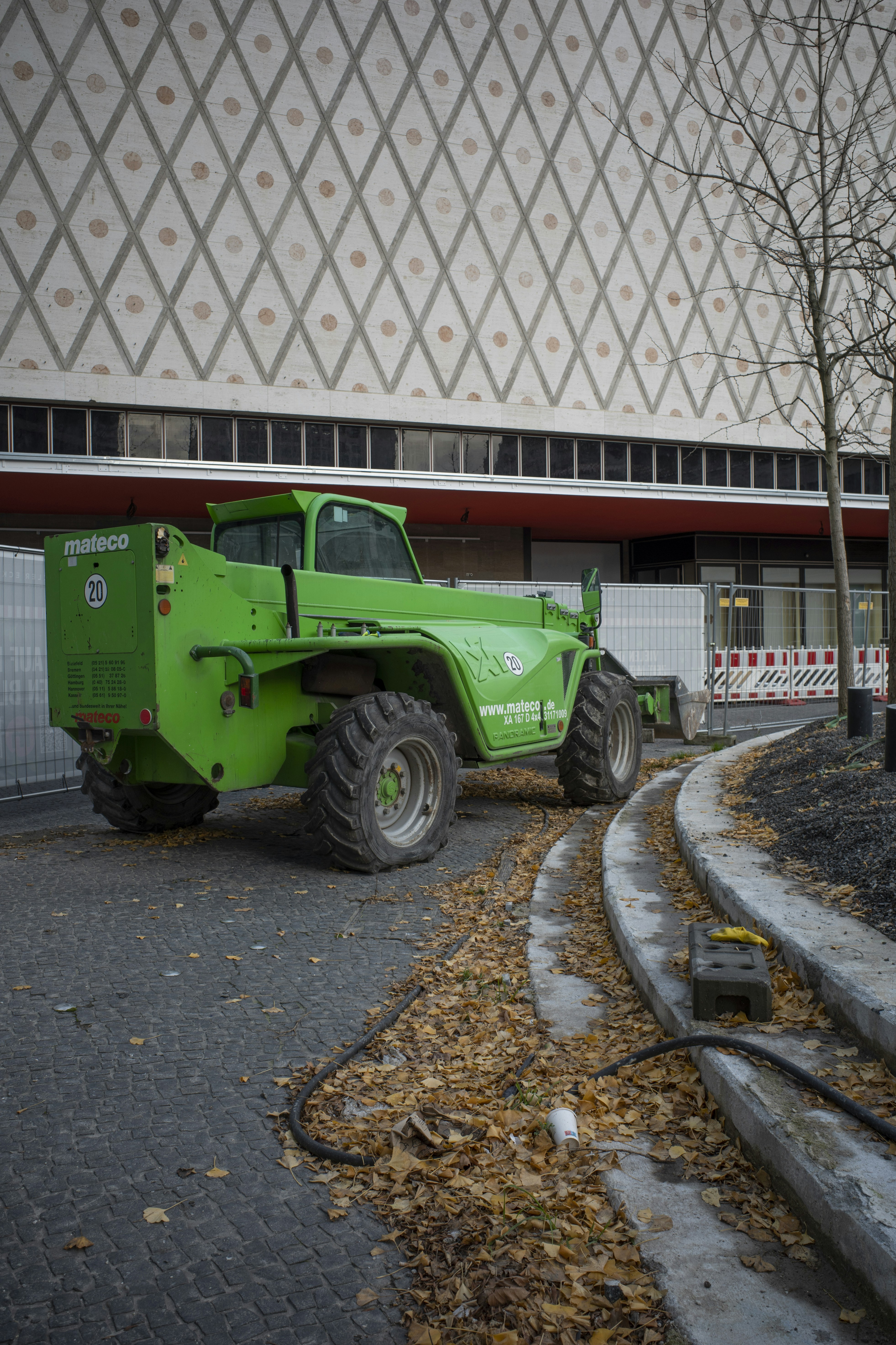 Green construction vehicle parked near building