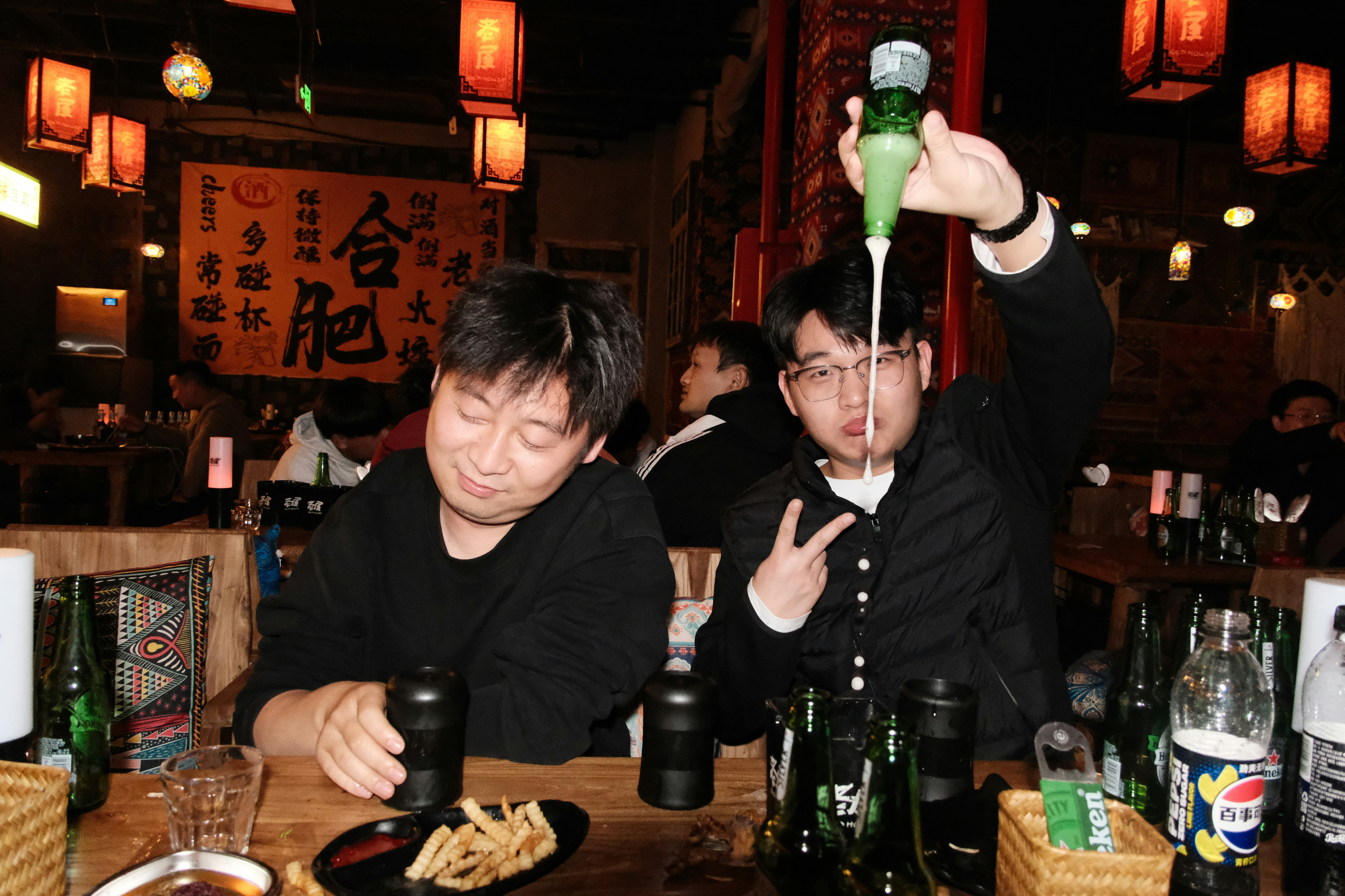 Two men at a bar with drinks and pouring drinks