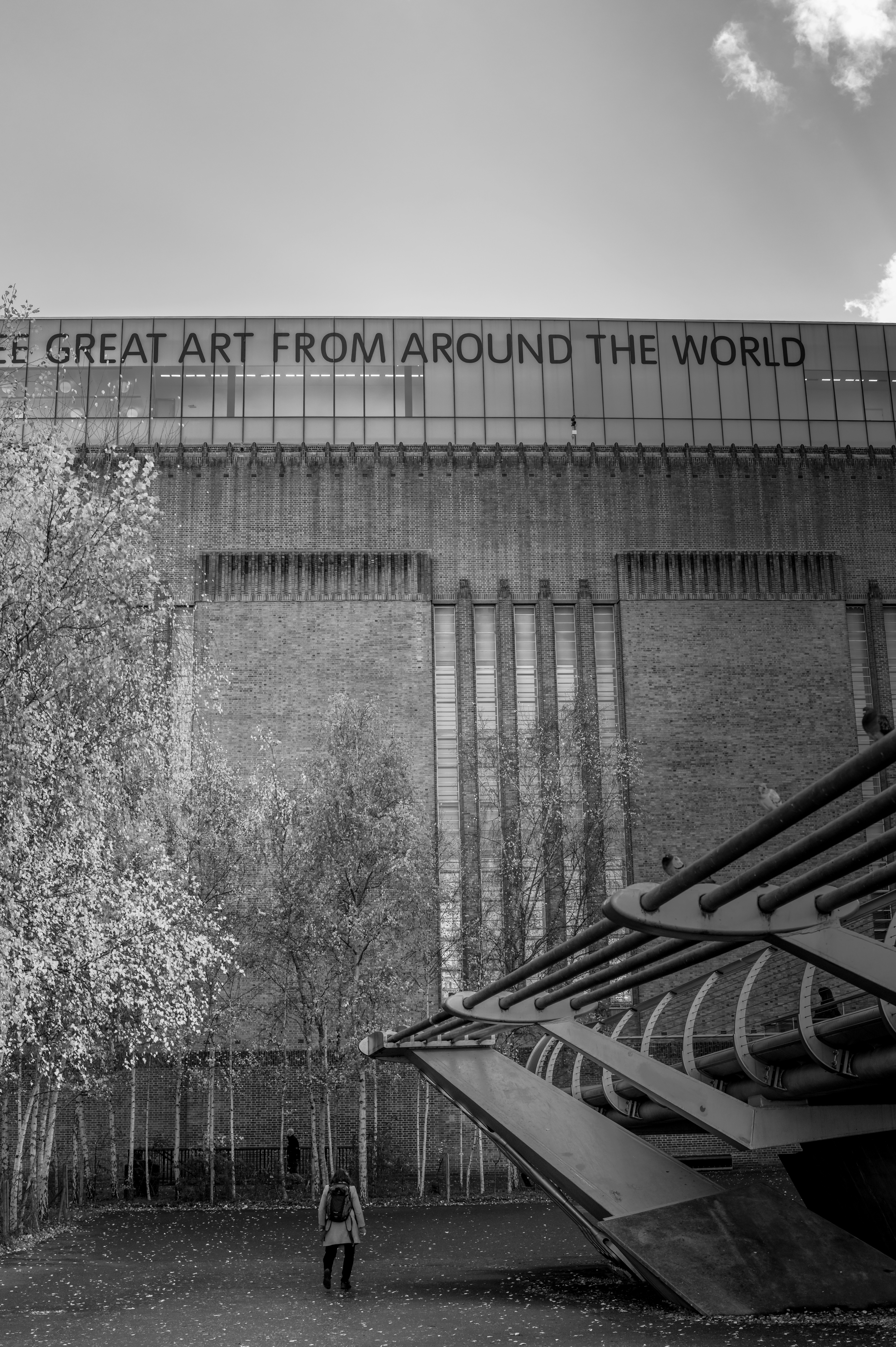 Una persona camina hacia un gran edificio de ladrillo con texto.