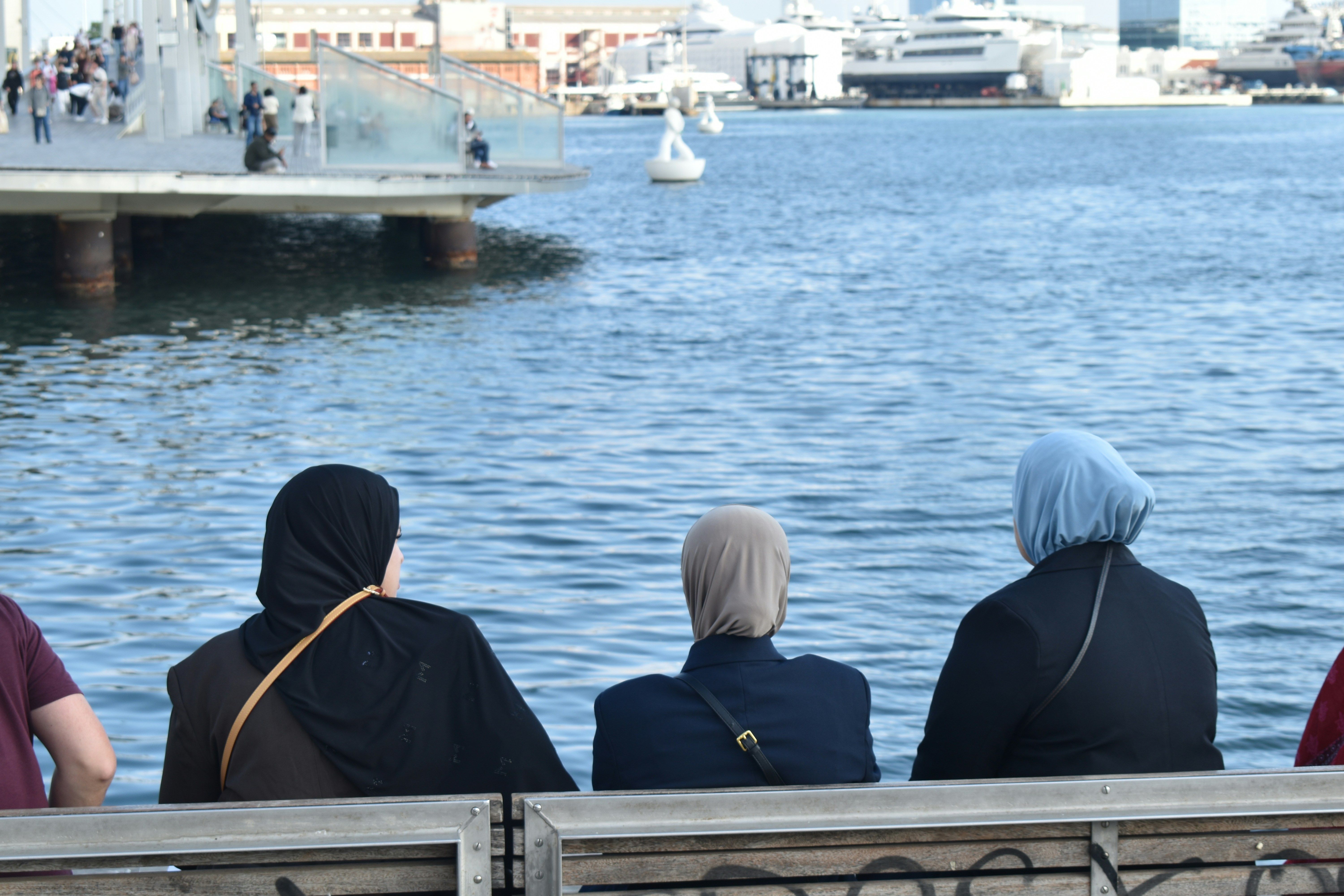 Three women wearing hijabs watch the water