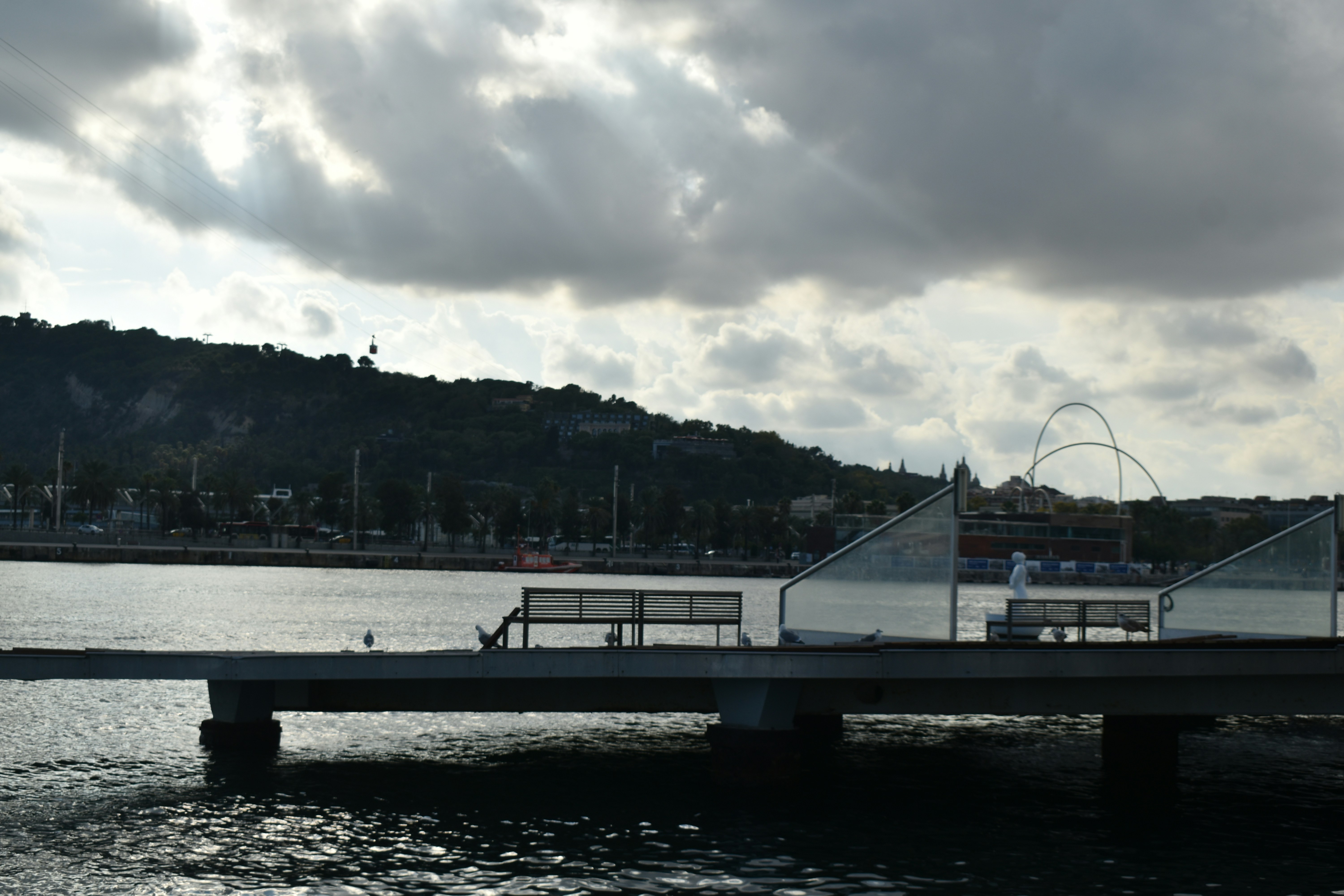 Pier with a view of a distant hill and clouds.