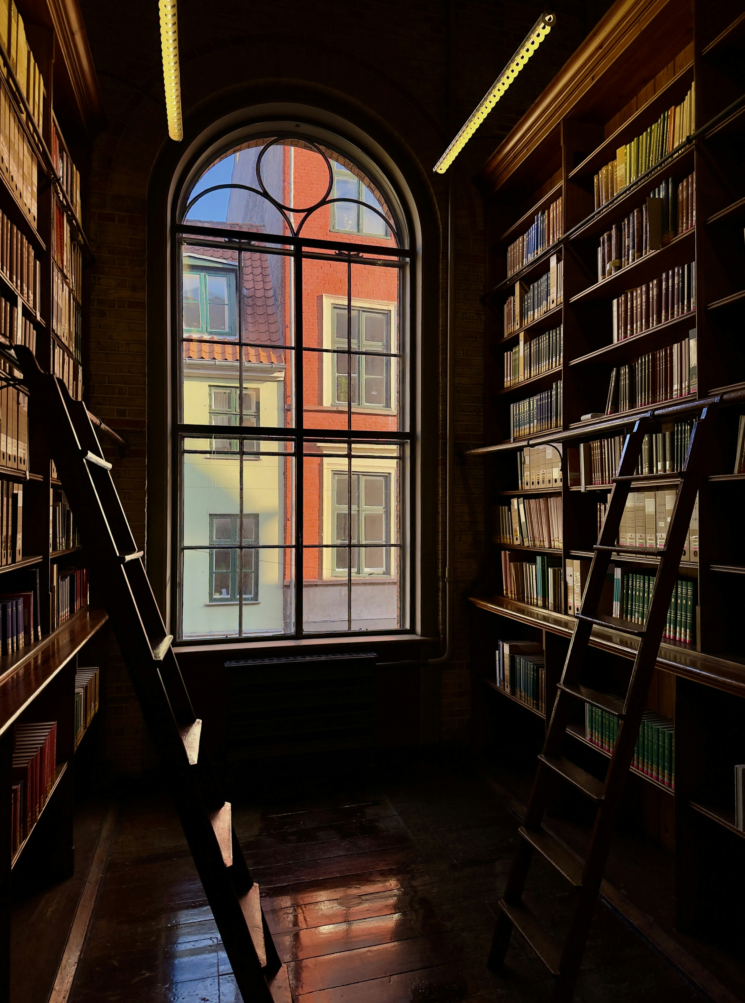 Alte Bibliothek mit Bogenfenster und bunten Gebäuden draußen.