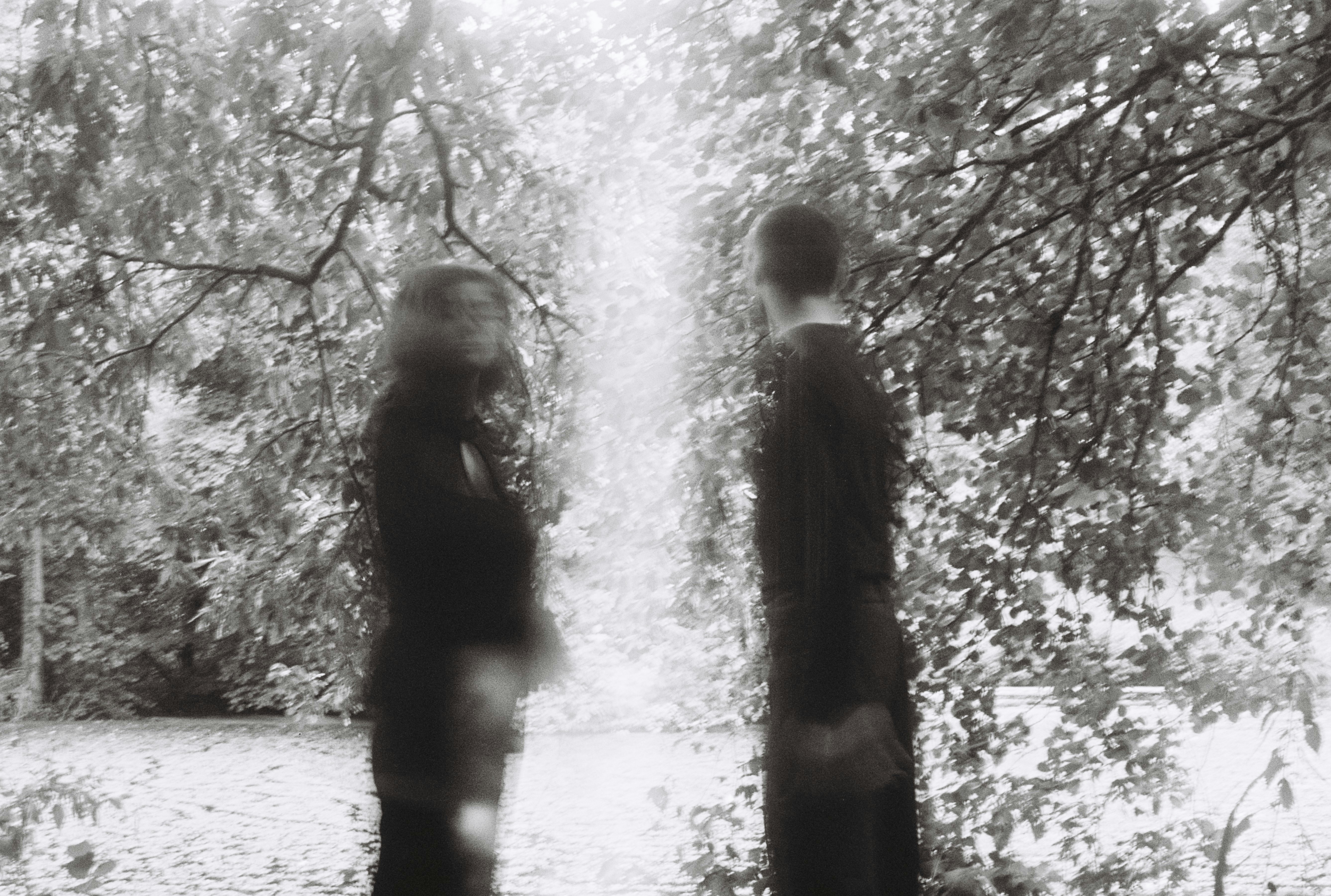 Two blurred figures stand in a park