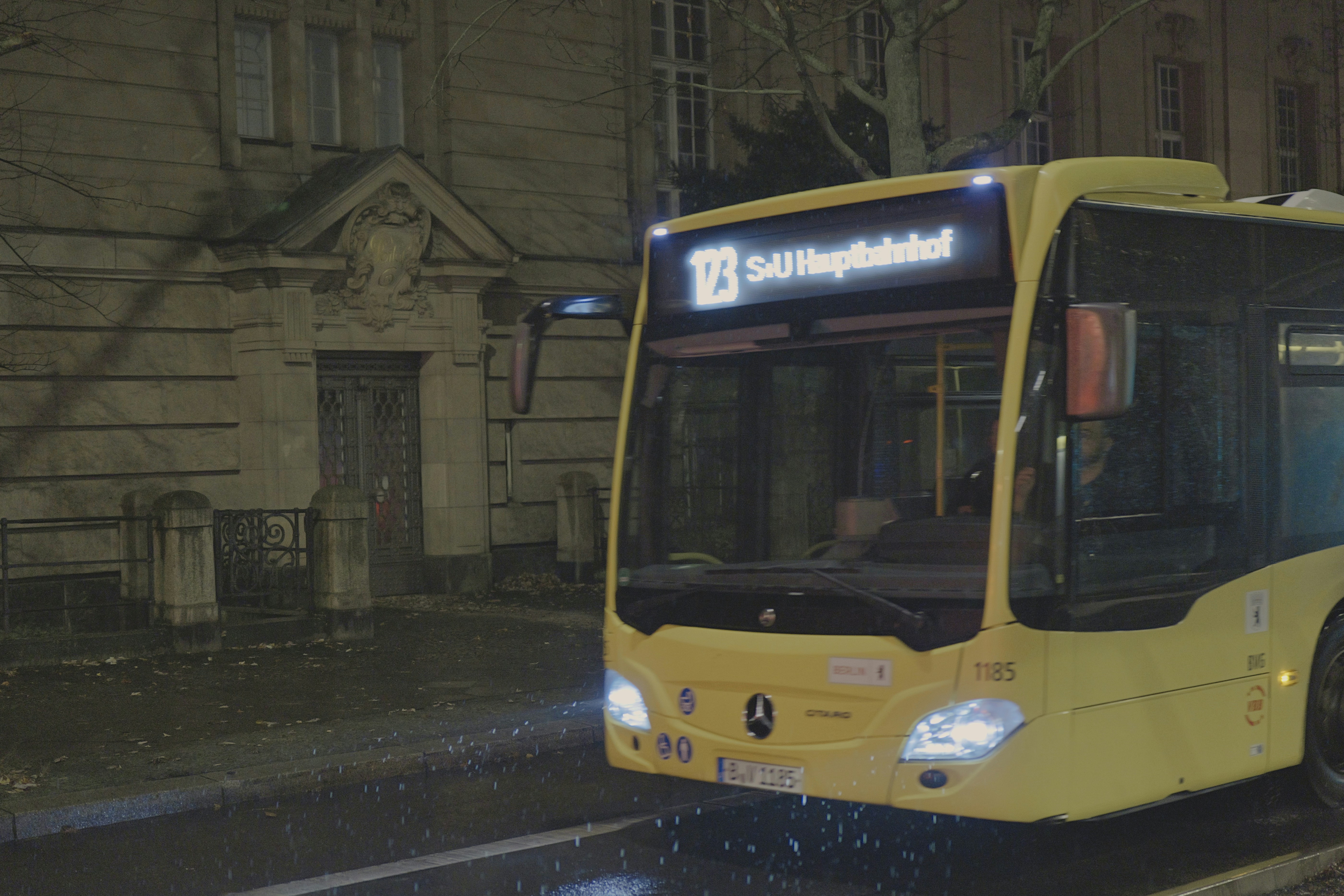 A yellow bus driving on a wet street at night. - a-yellow-bus-driving-on-a-wet-street-at-night-uRR3YZu2S8w
