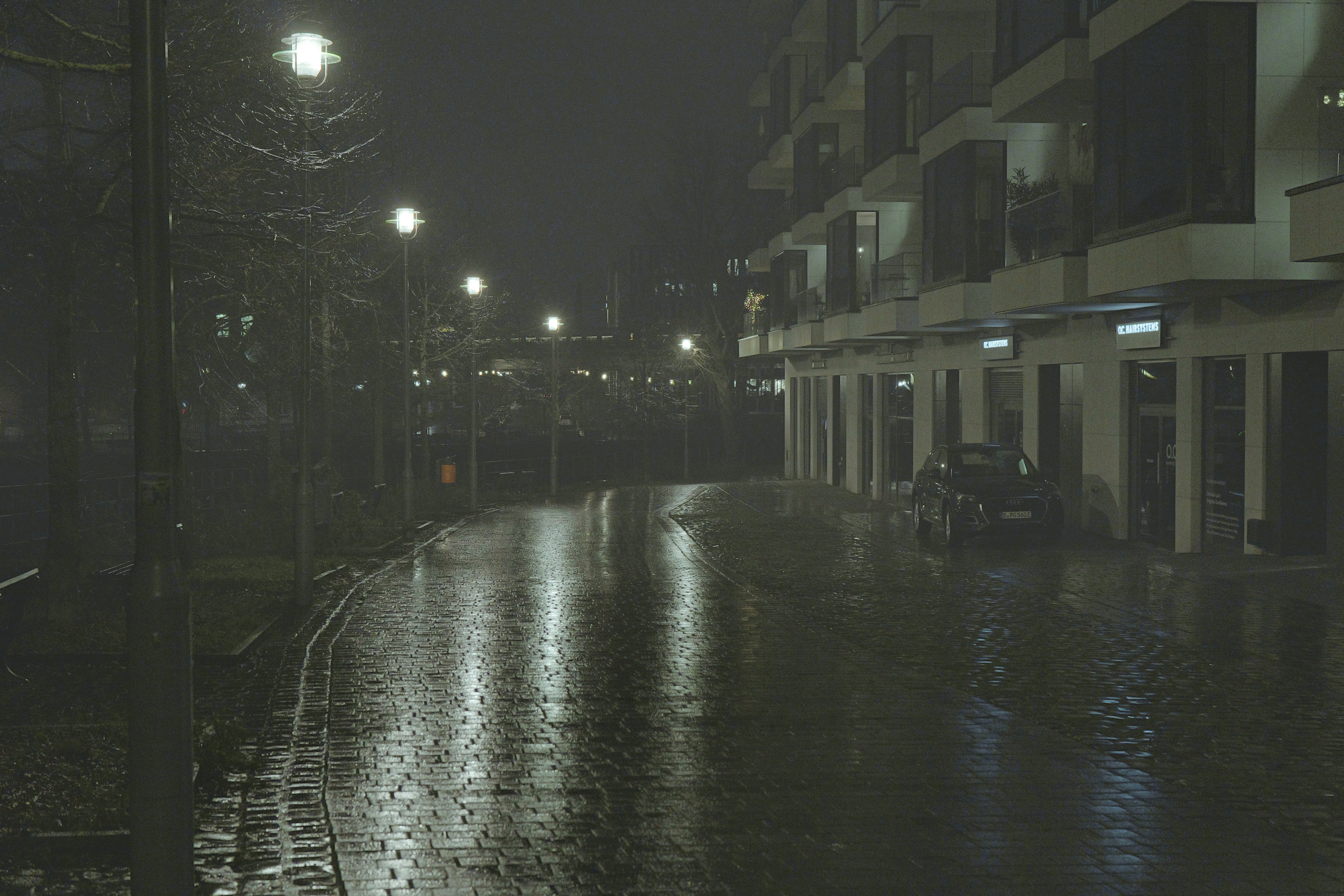 A street at night with reflections on wet pavement. - a-street-at-night-with-reflections-on-wet-pavement-Yqx1L4WdTvc