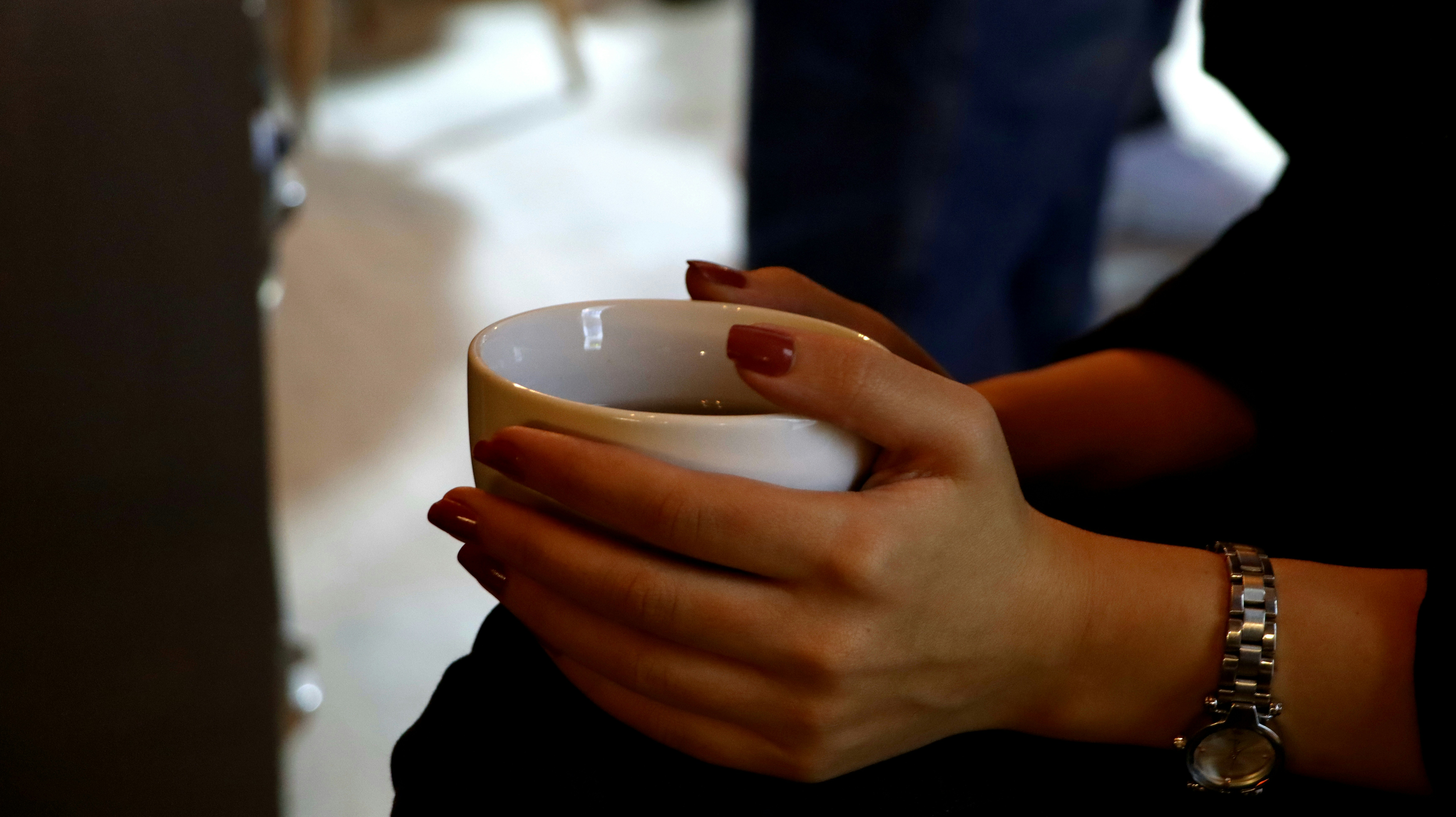 Woman holding a cup of coffee with red nails.