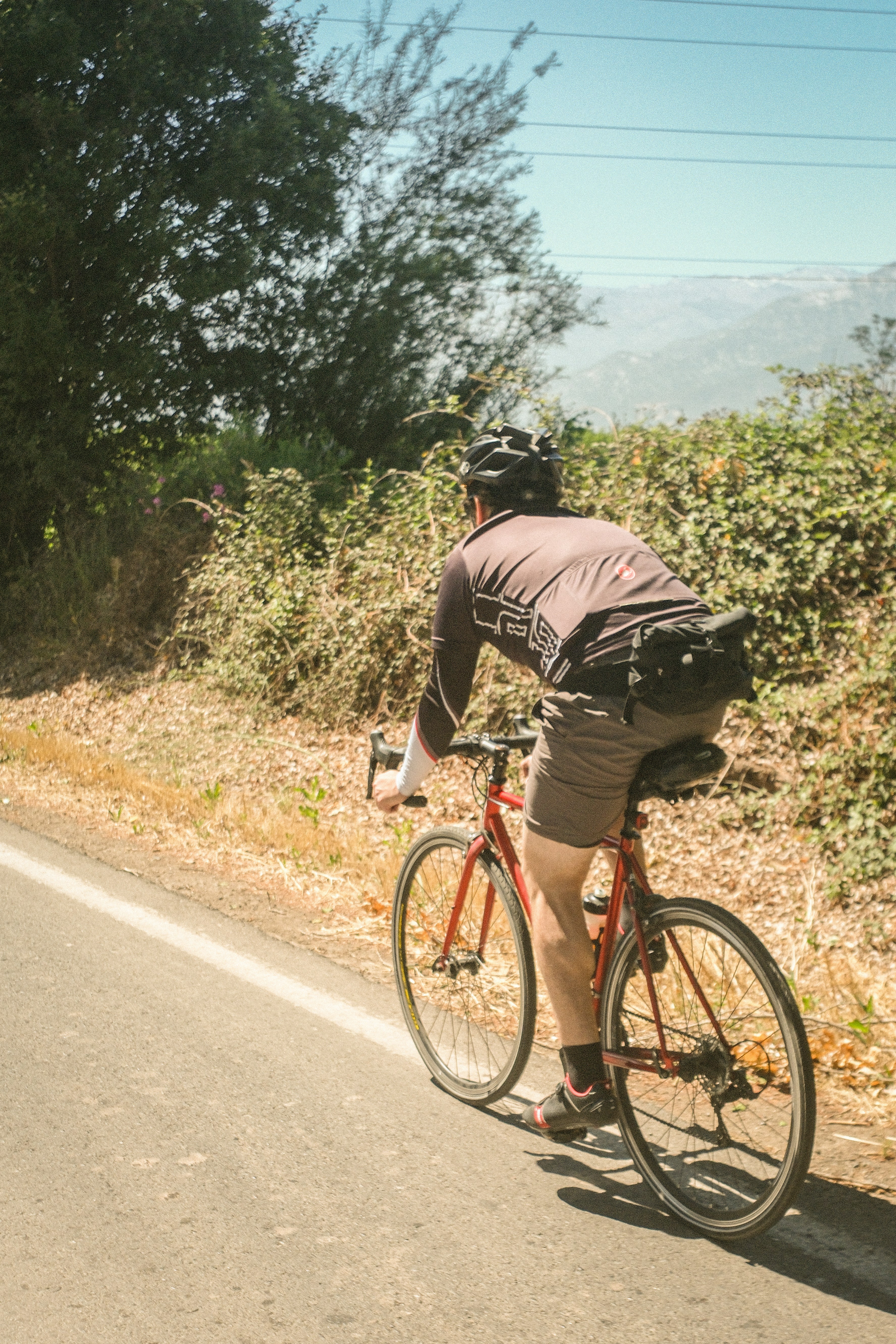 Man cycling on a road with green foliage