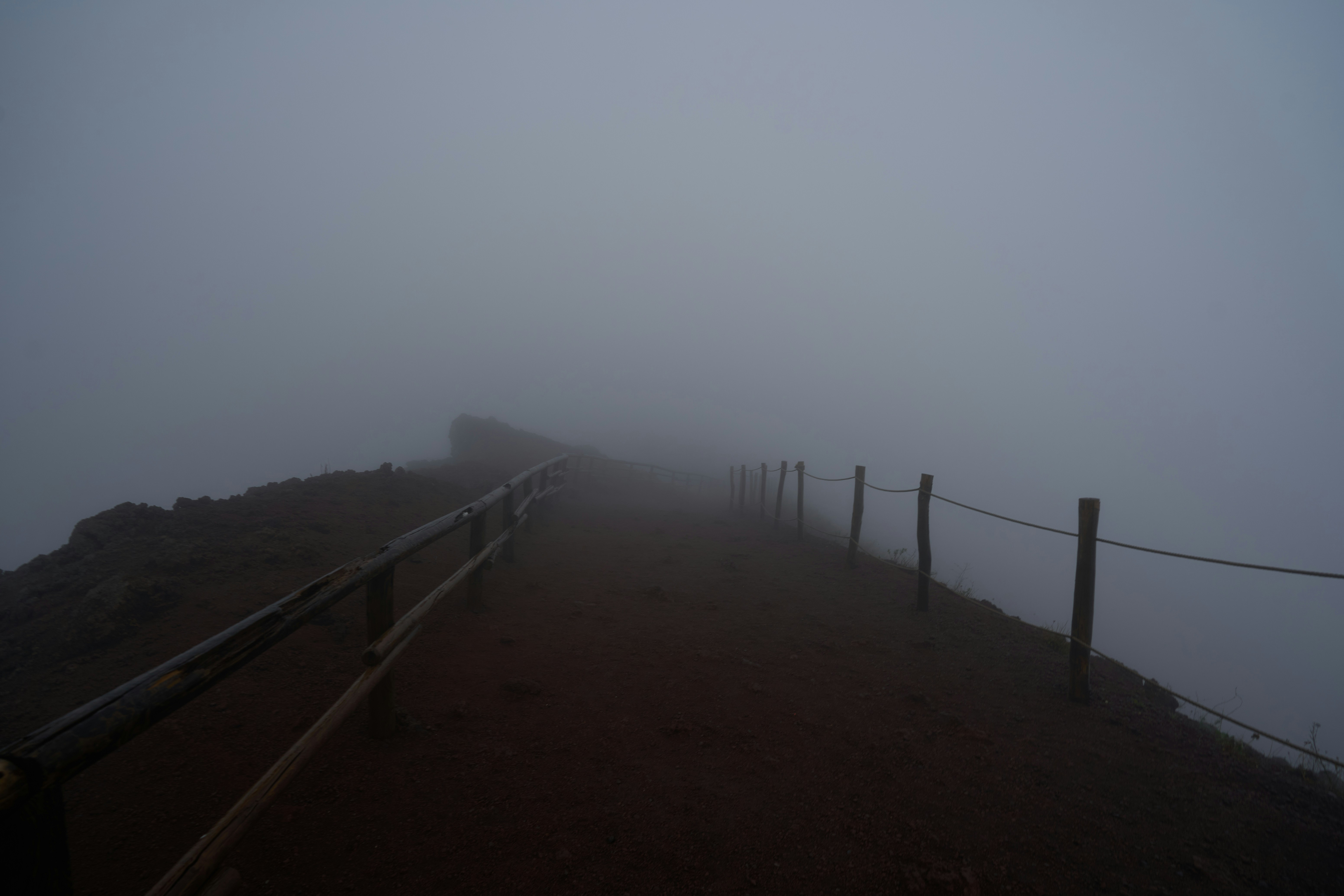 A foggy mountain path with a wooden fence
