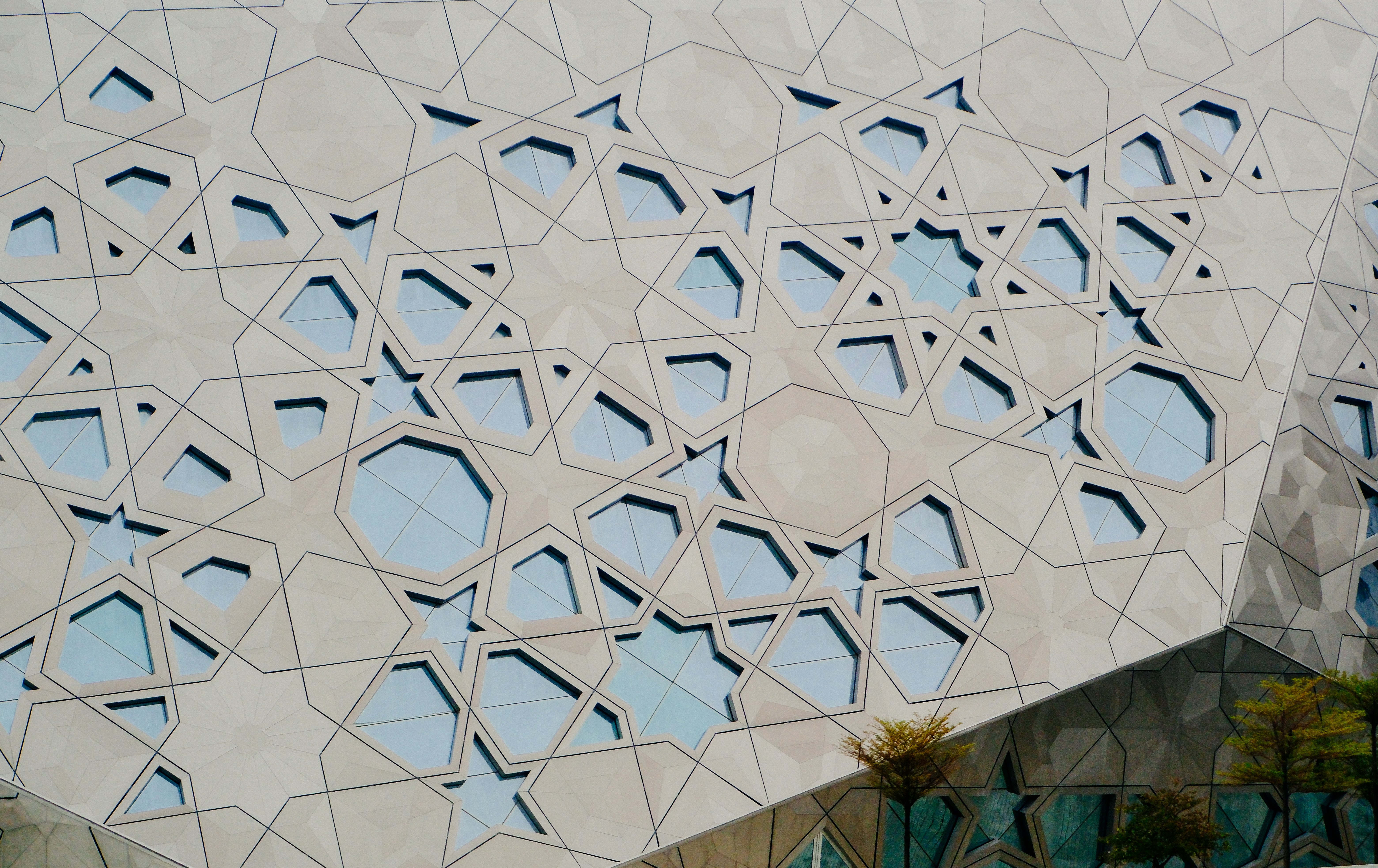 Modern bina cephesi, karmaşık geometrik desenler ve mavi pencerelerle.