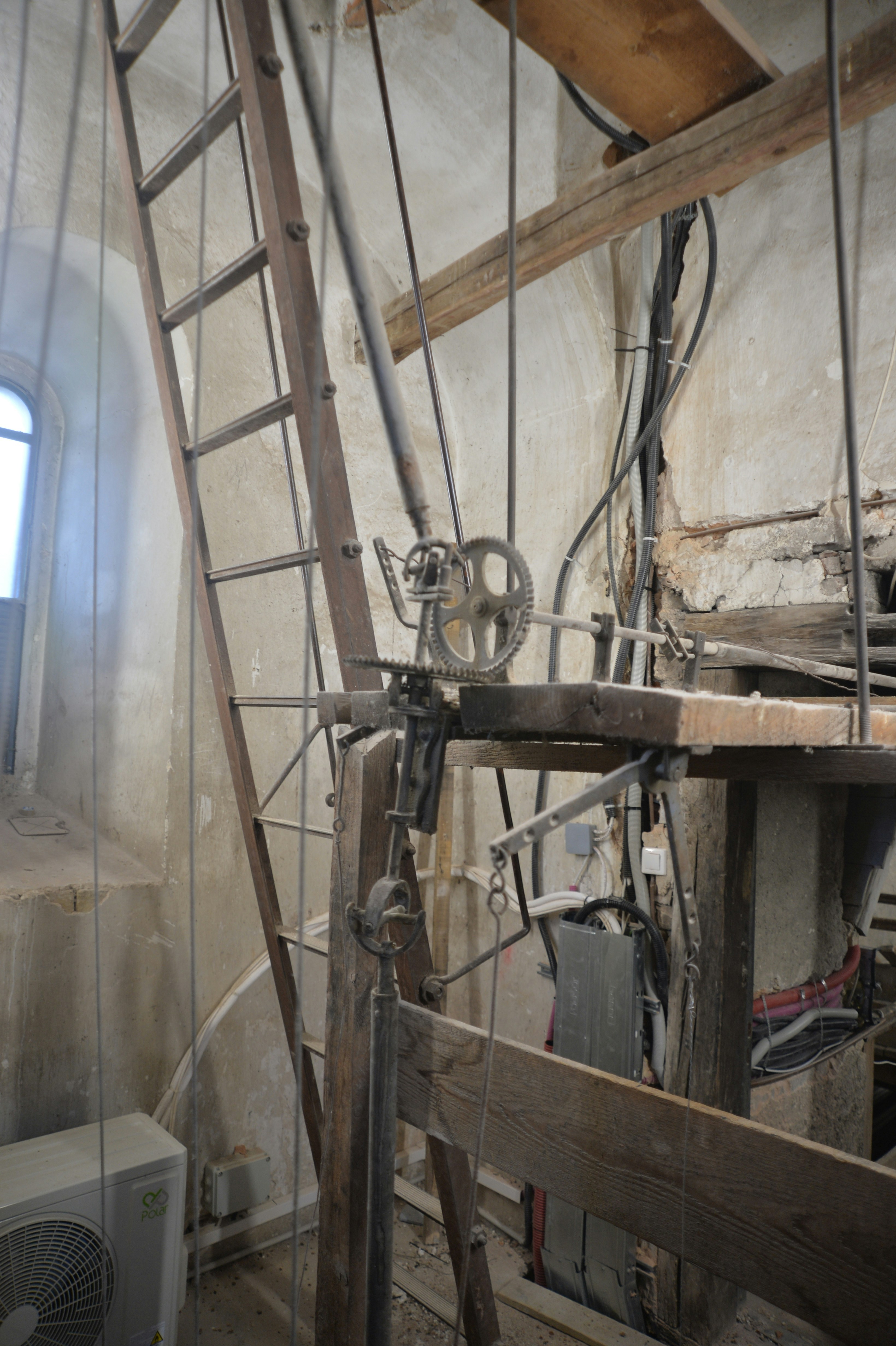 Wooden ladder and machinery inside a bell tower.