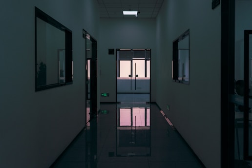 Dark, modern hallway with reflective floor and windows.