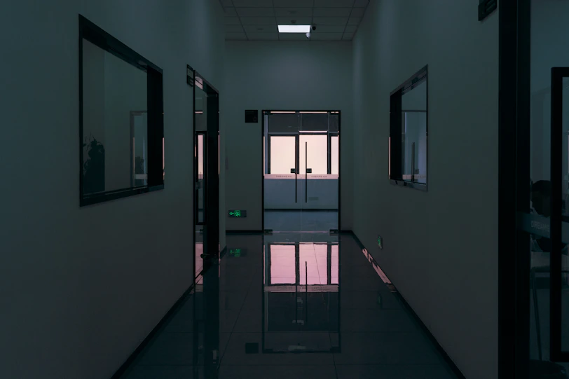 Dark, modern hallway with reflective floor and windows.