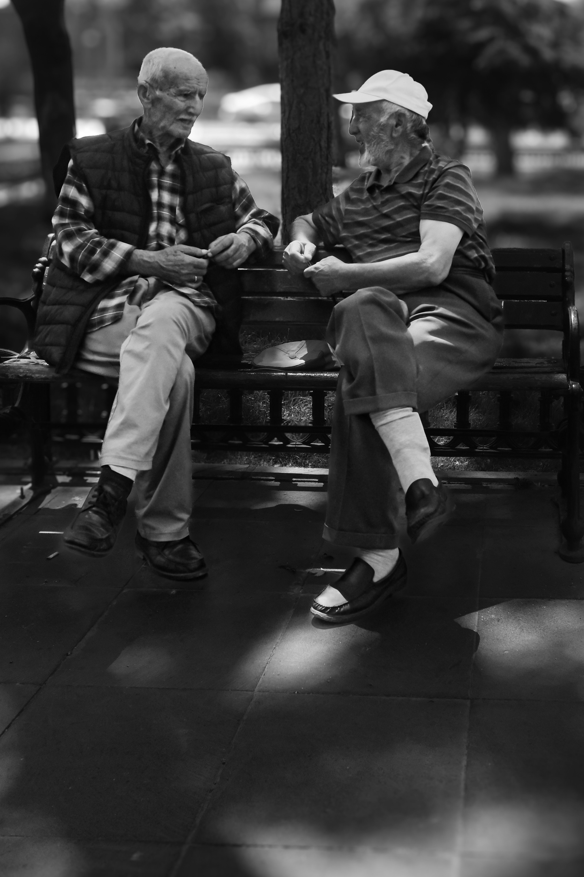 Two older men sitting on a park bench, talking.