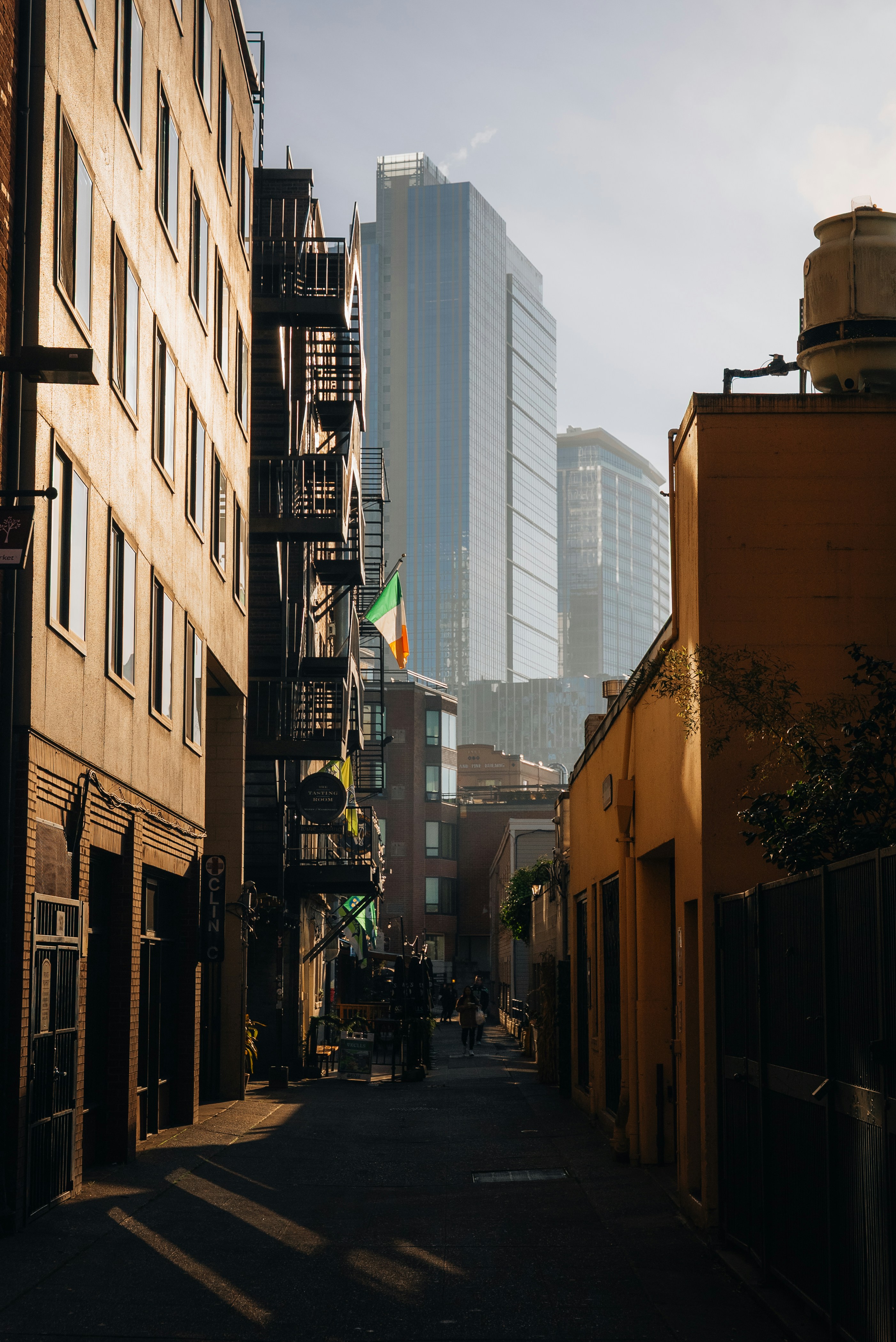 Narrow city alley with tall buildings and fire escapes
