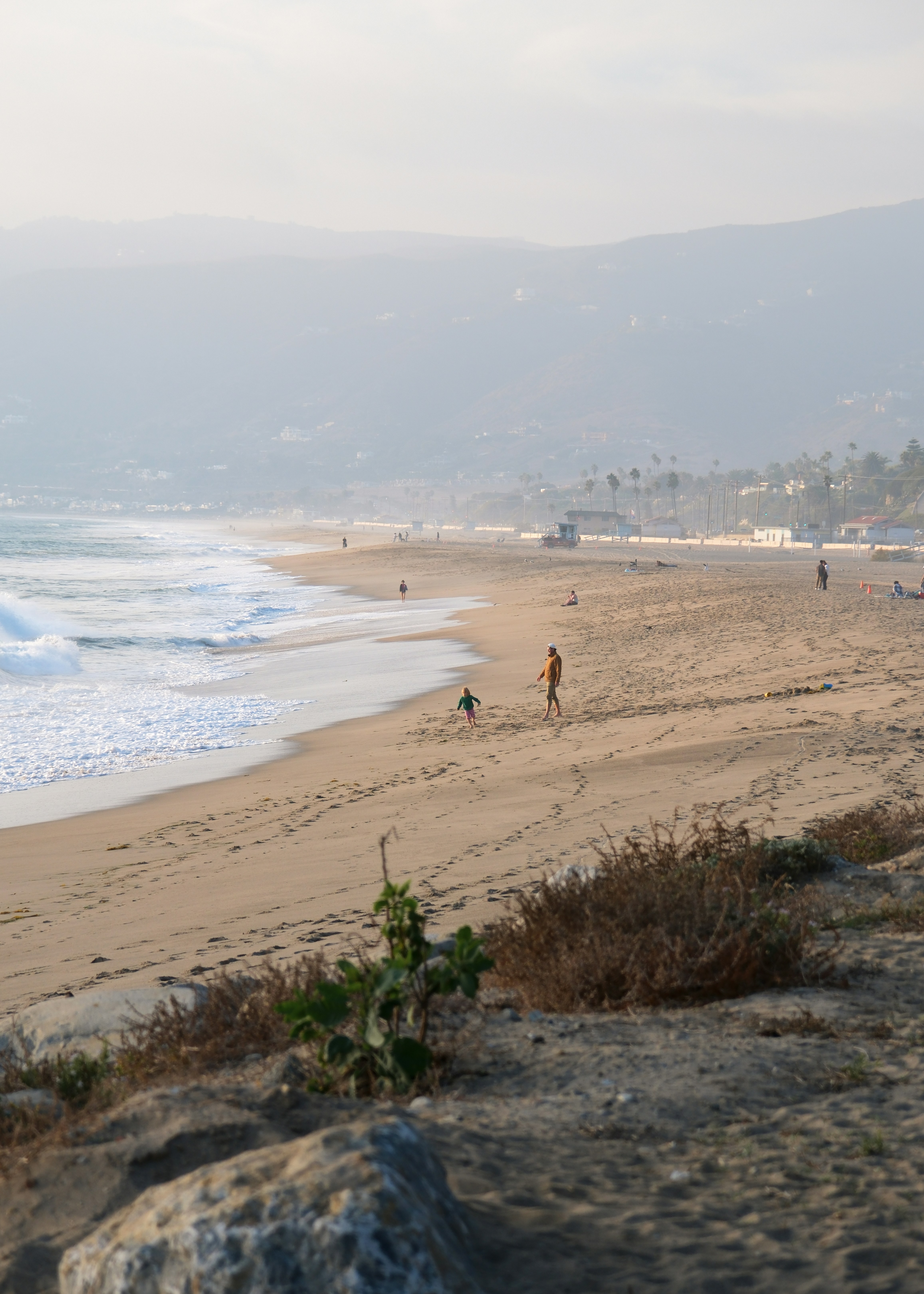 Persone che camminano su una spiaggia sabbiosa con onde dell'oceano.