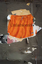 Orange shorts with "unfashionable" text on wall
