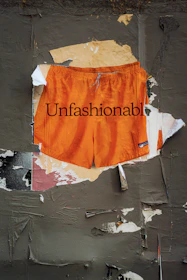 Orange shorts with "unfashionable" text on wall