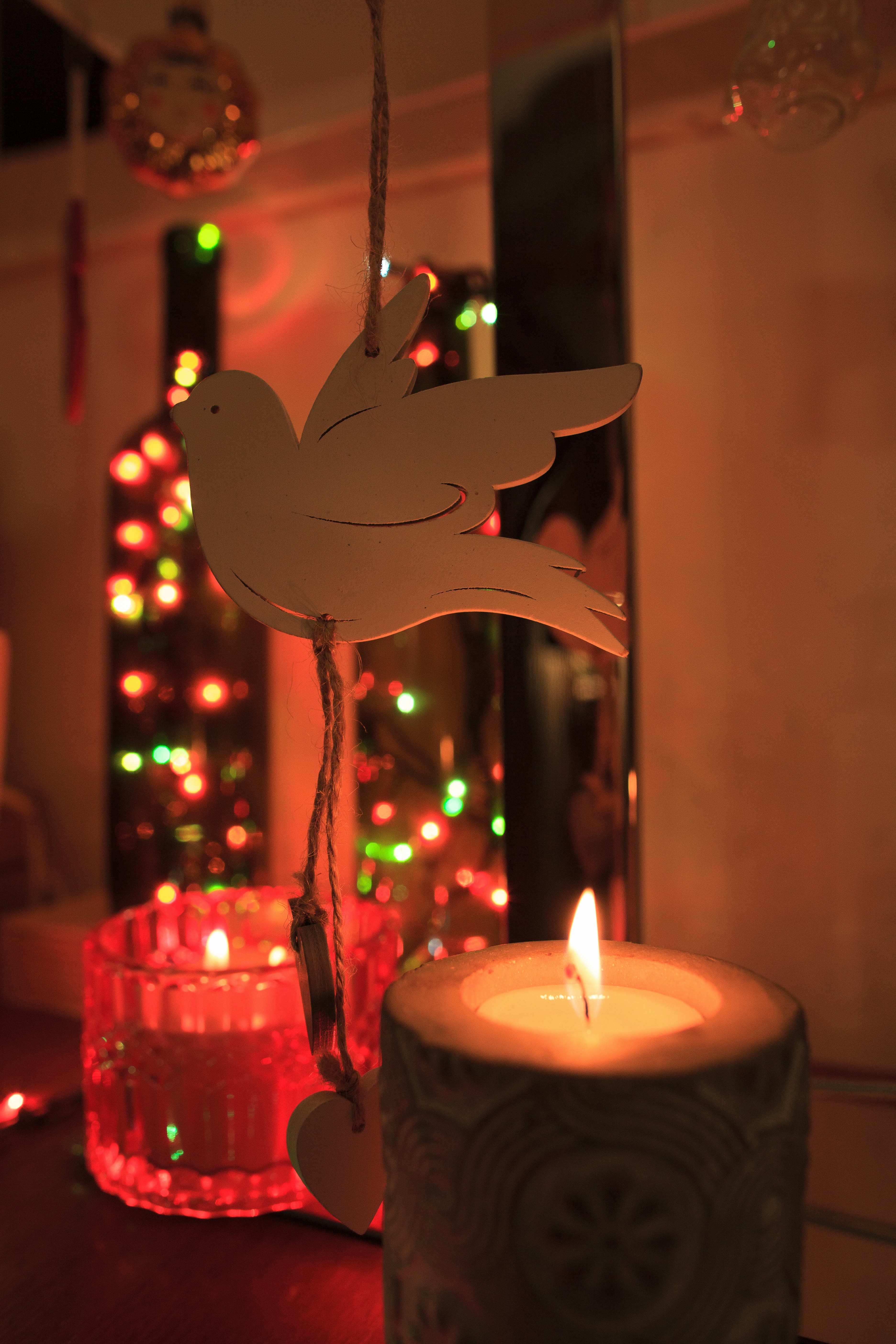 Candles and festive lights with a dove ornament.