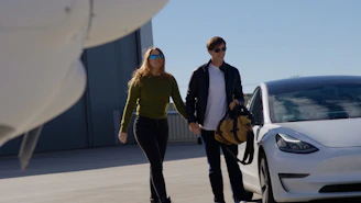 Couple walking towards a white car near airplane