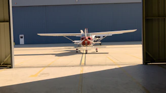 Small airplane exiting a hangar on a sunny day.