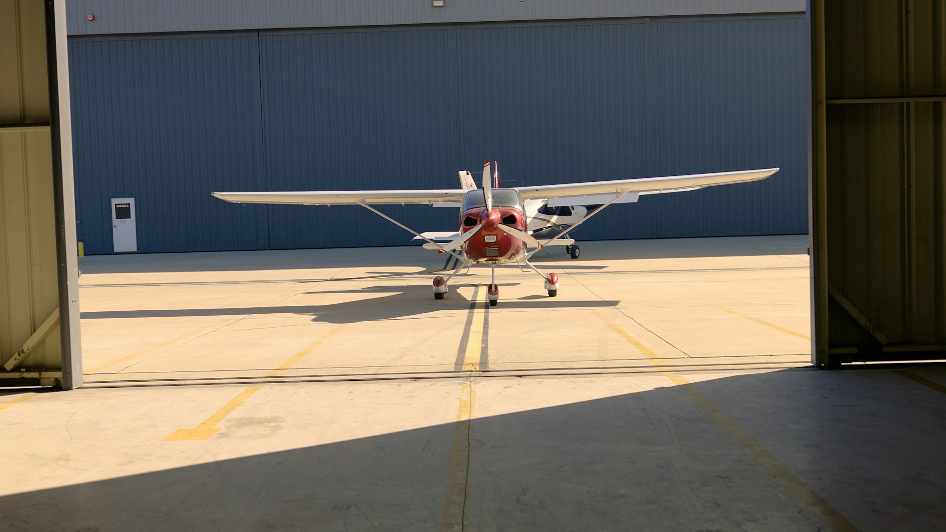 Small airplane exiting a hangar on a sunny day.