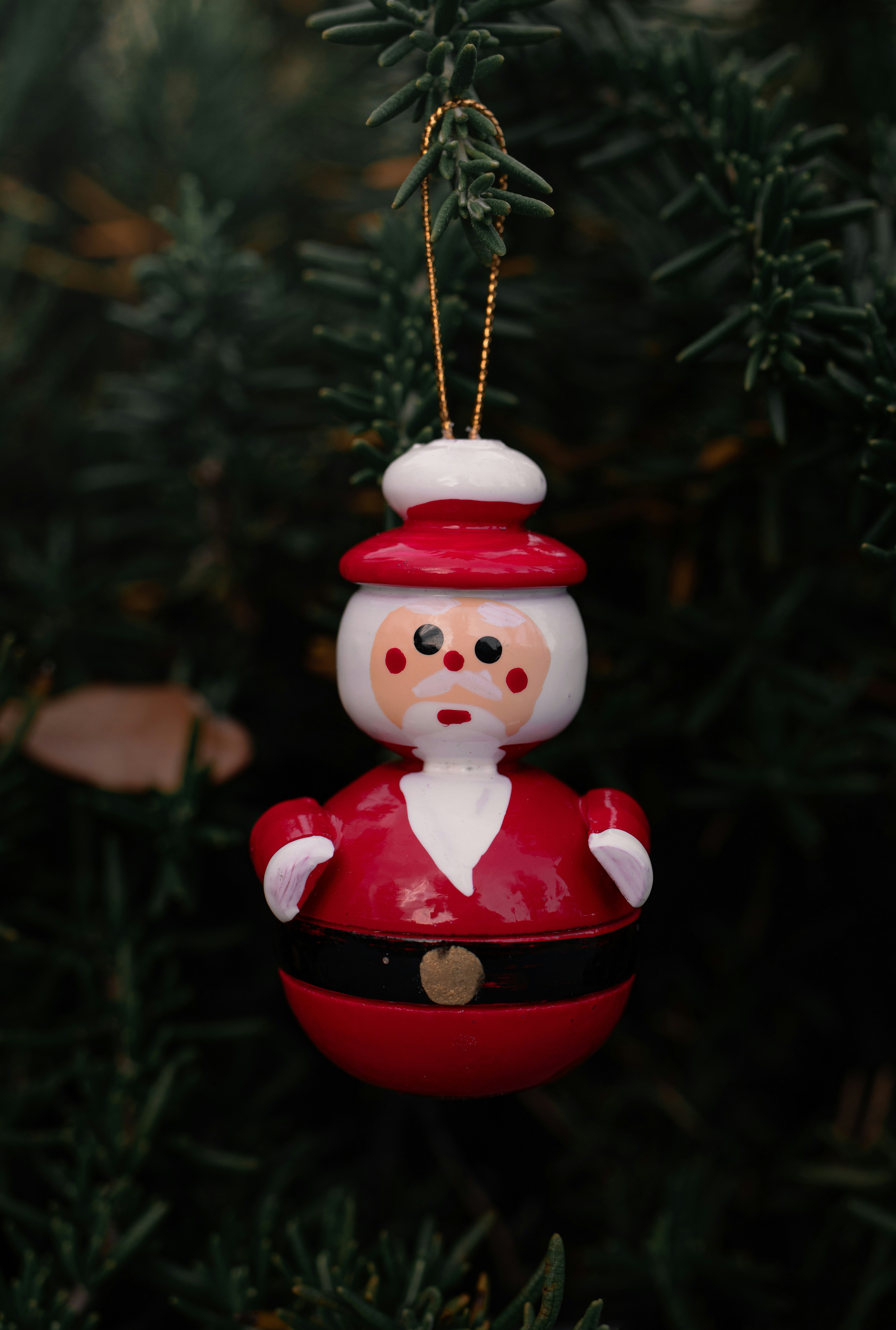 A festive santa claus ornament hangs on a christmas tree.