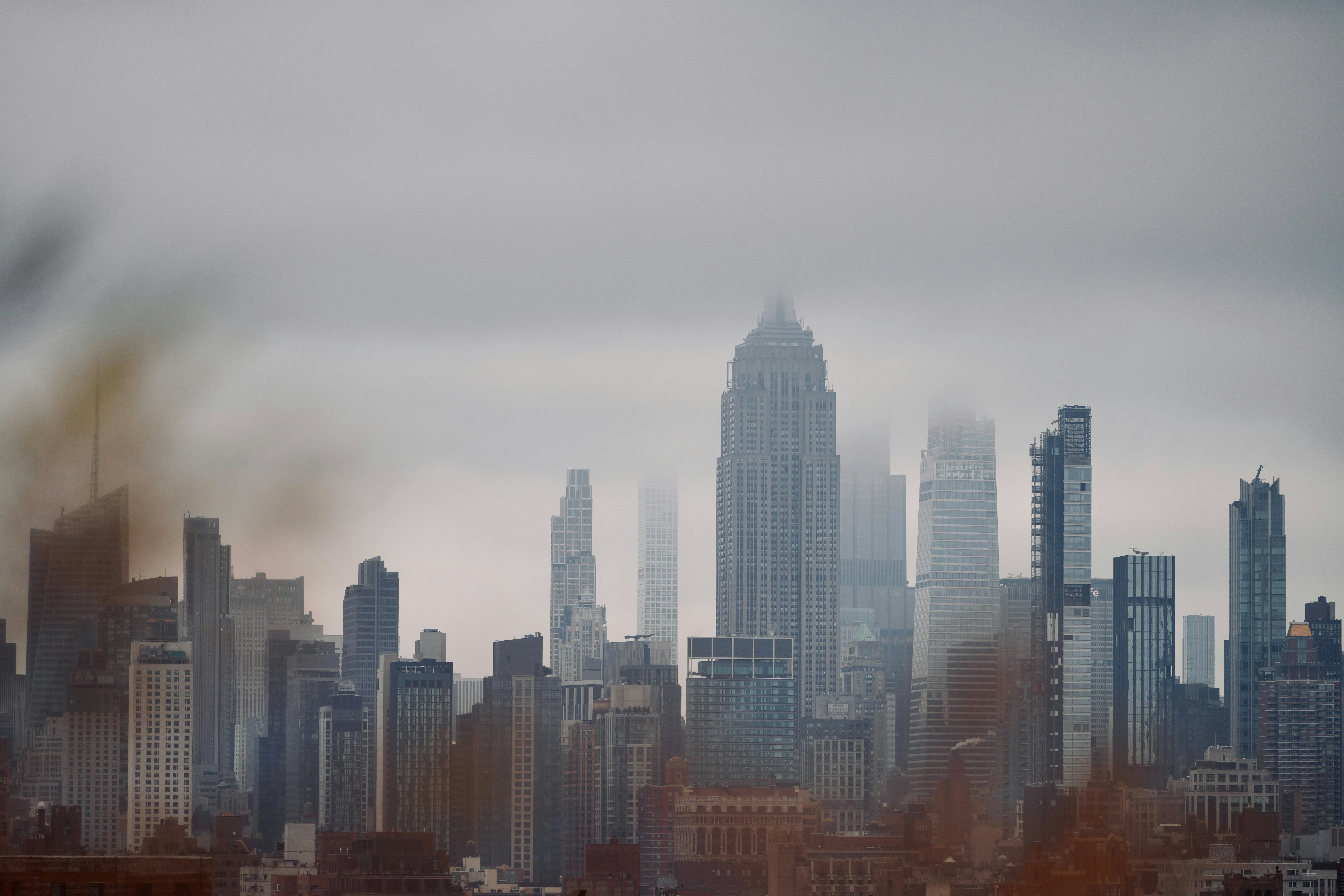 Foggy cityscape with tall modern buildings in the distance.