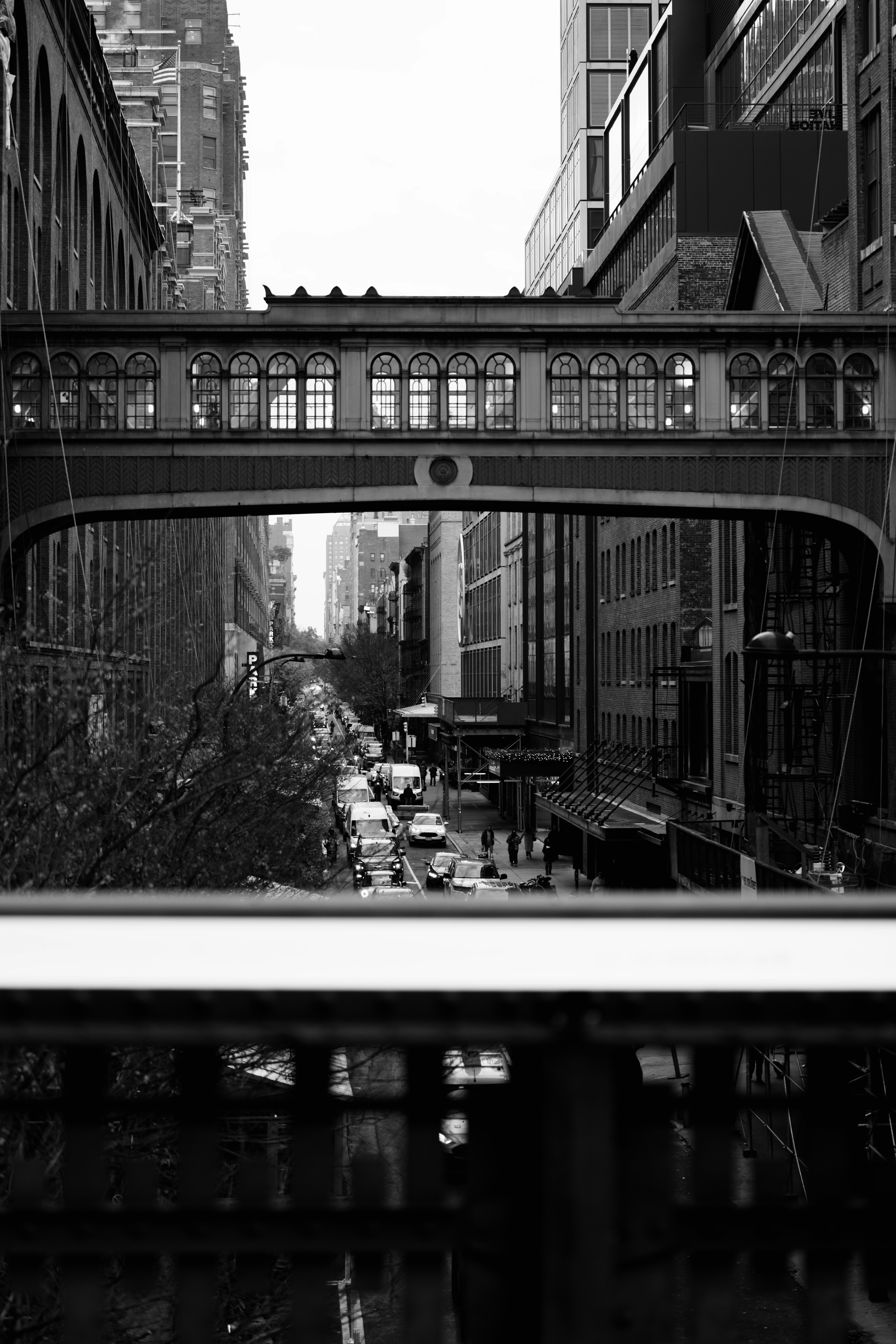 Black and white cityscape with elevated walkway and street traffic
