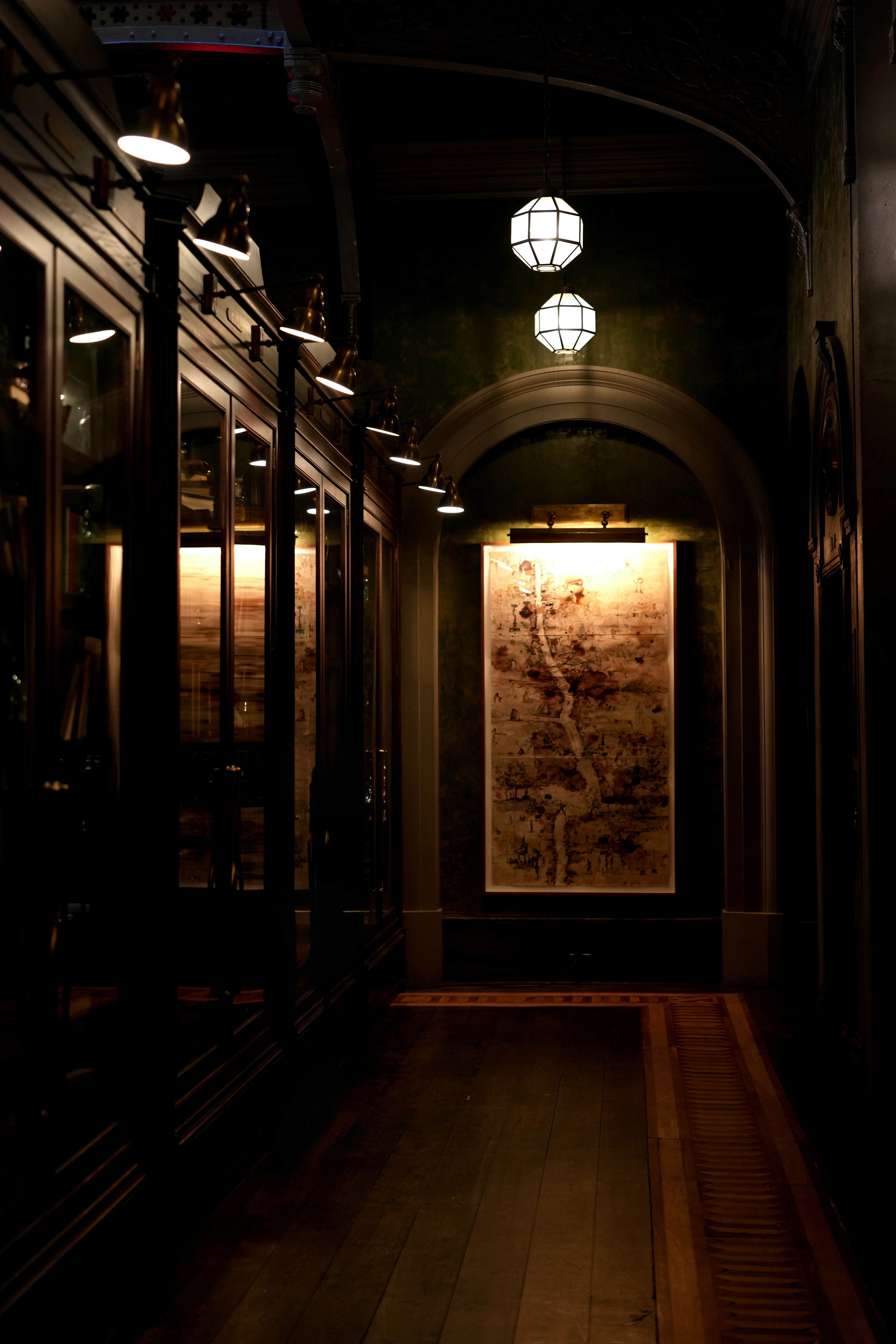 Dimly lit hallway with artwork and globe lights