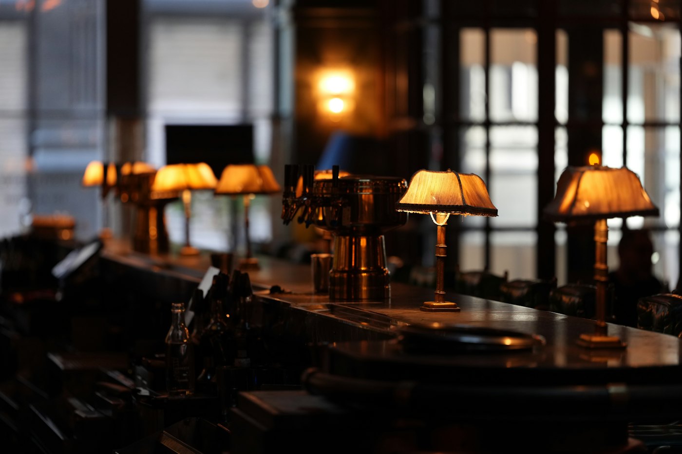 A row of small lamps glowing along a bar counter in a dim room