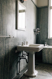 A vintage bathroom with a pedestal sink and bathtub.