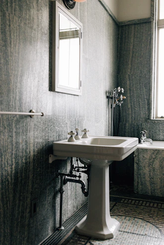 A vintage bathroom with a pedestal sink and bathtub.