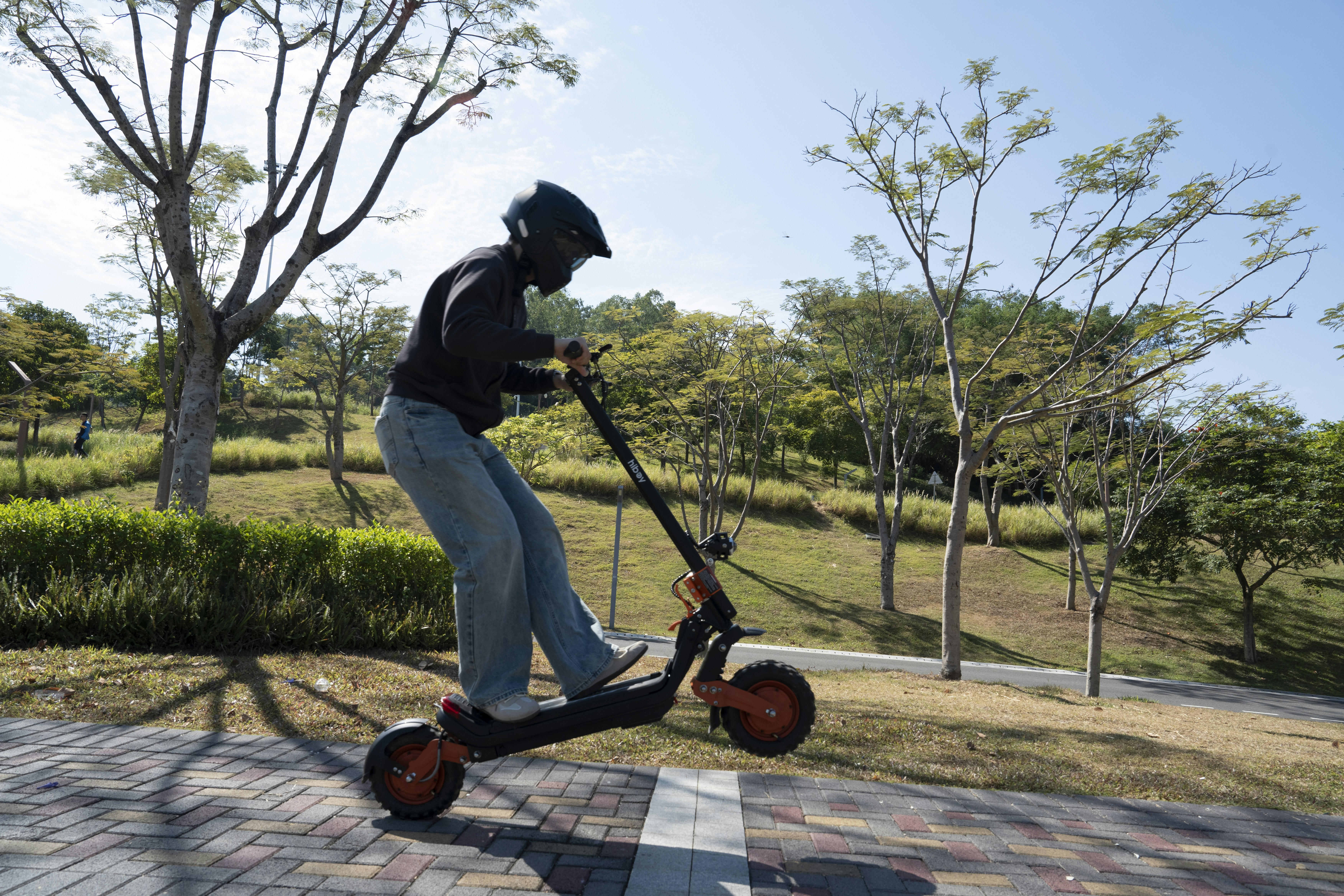 Person riding an electric scooter on a paved path.