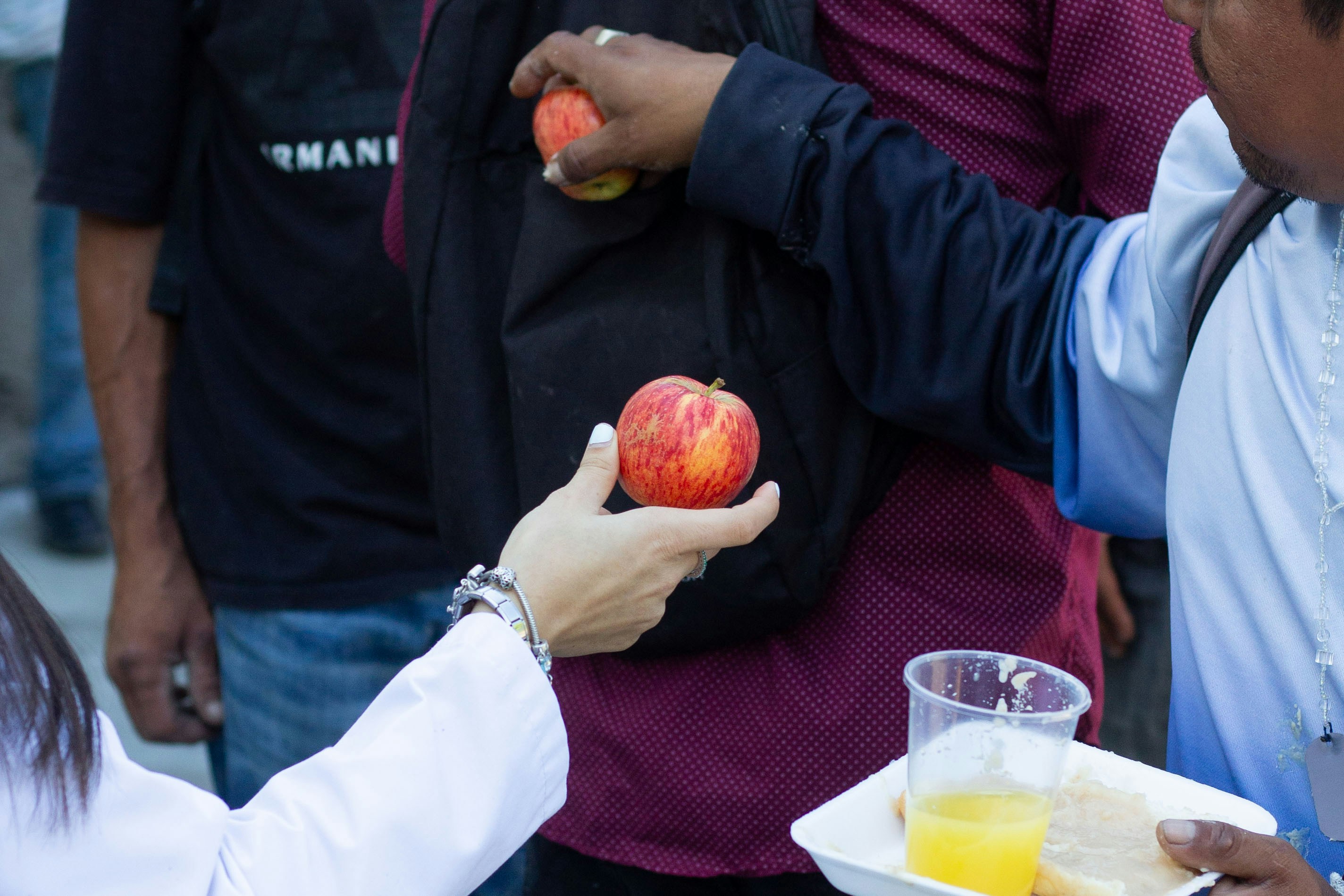 Hands offering and receiving apples and juice
