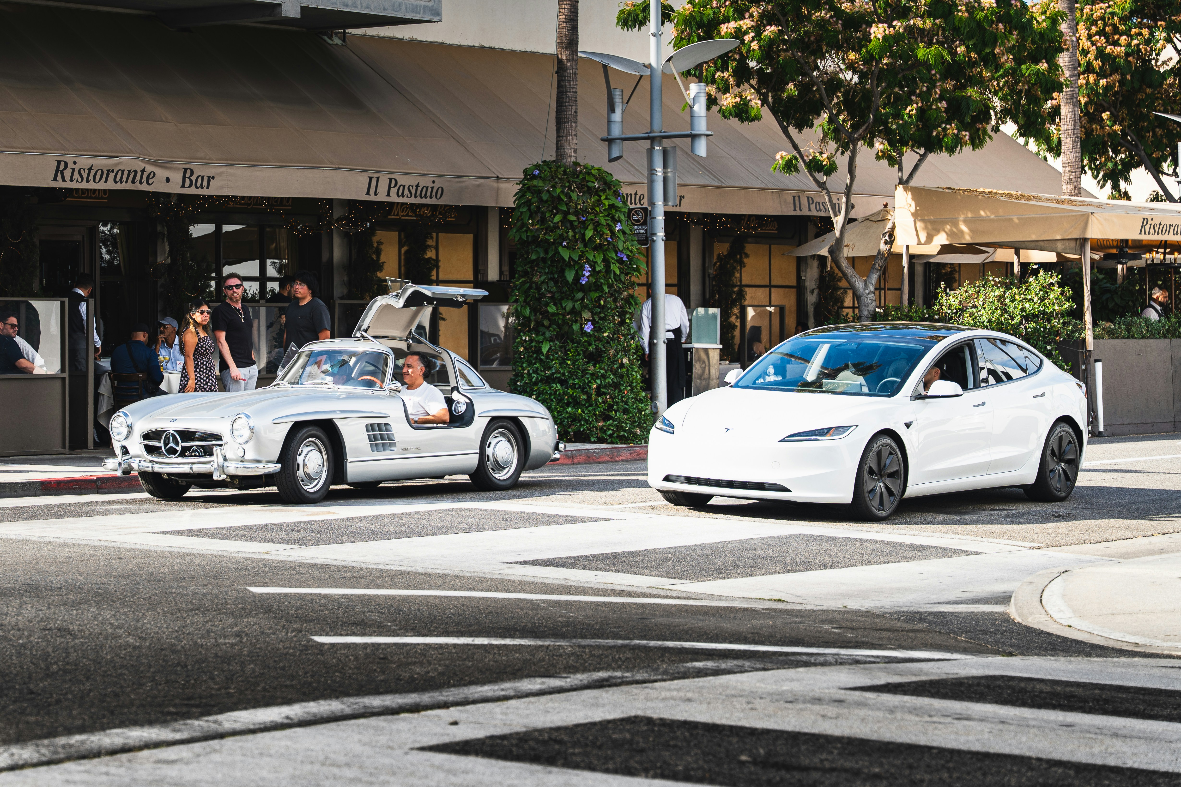 Classic silver mercedes and white tesla on street.