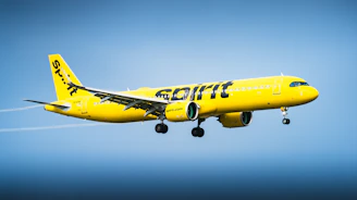 A yellow spirit airlines airplane flying in the sky.