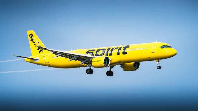 A yellow spirit airlines airplane flying in the sky.