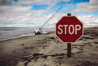 Stop sign on a beach with a beached boat.