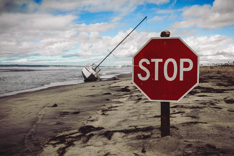 Stop sign on a beach with a beached boat.