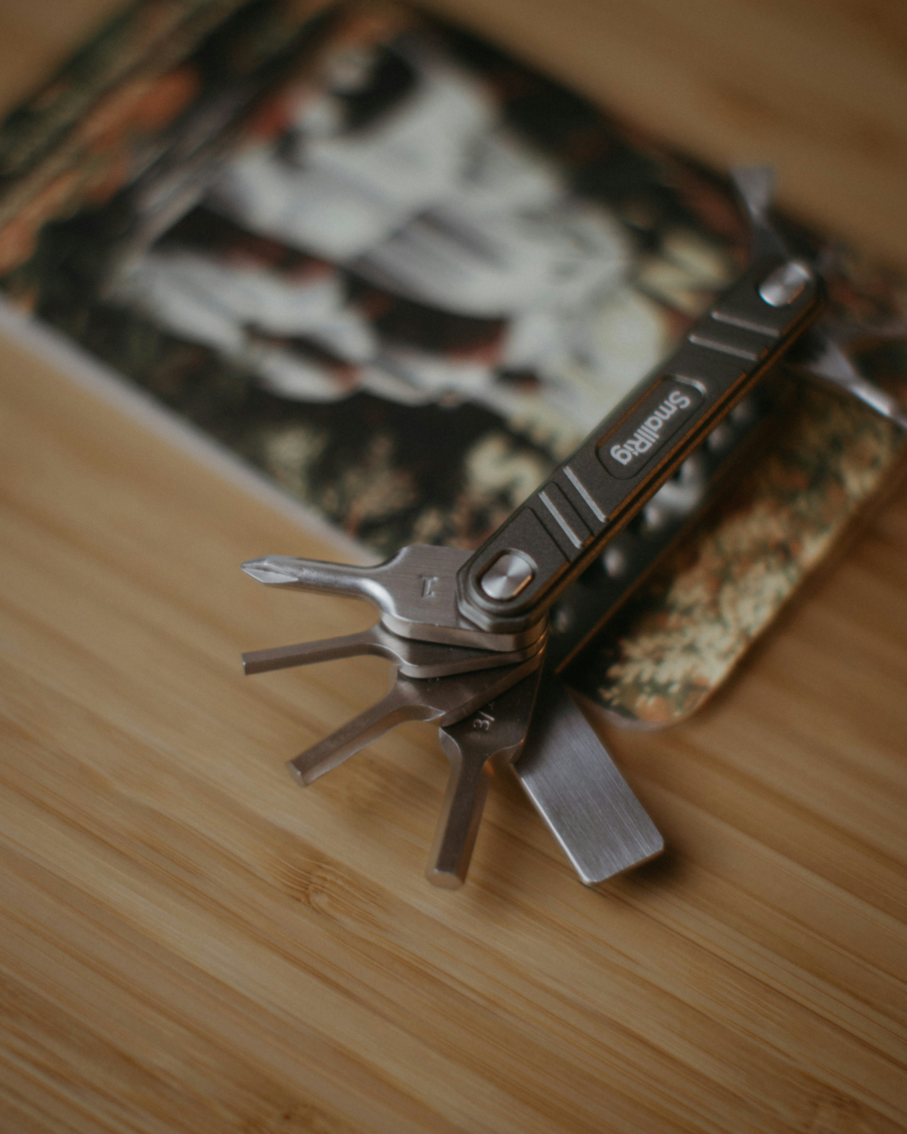 Multitool with various attachments on wooden surface.